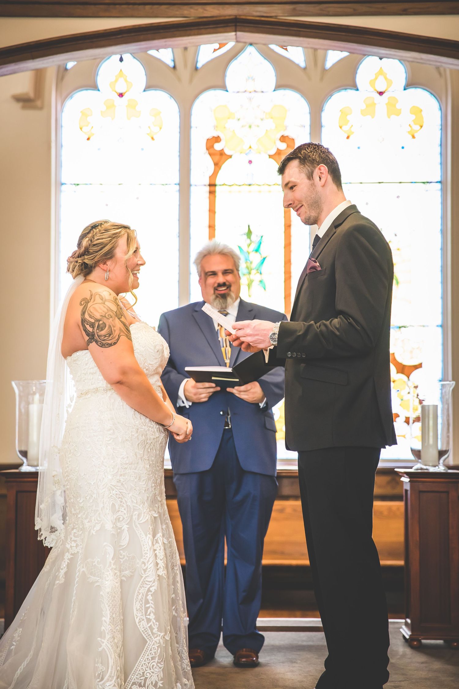 Wedding ceremony in front of ornate stained glass windows in a traditional church.