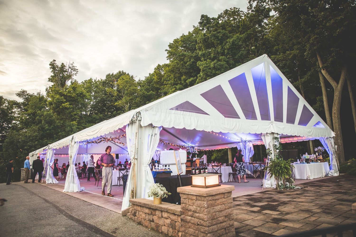 Large white wedding tents set up outdoors under cloudy skies for an elegant reception.