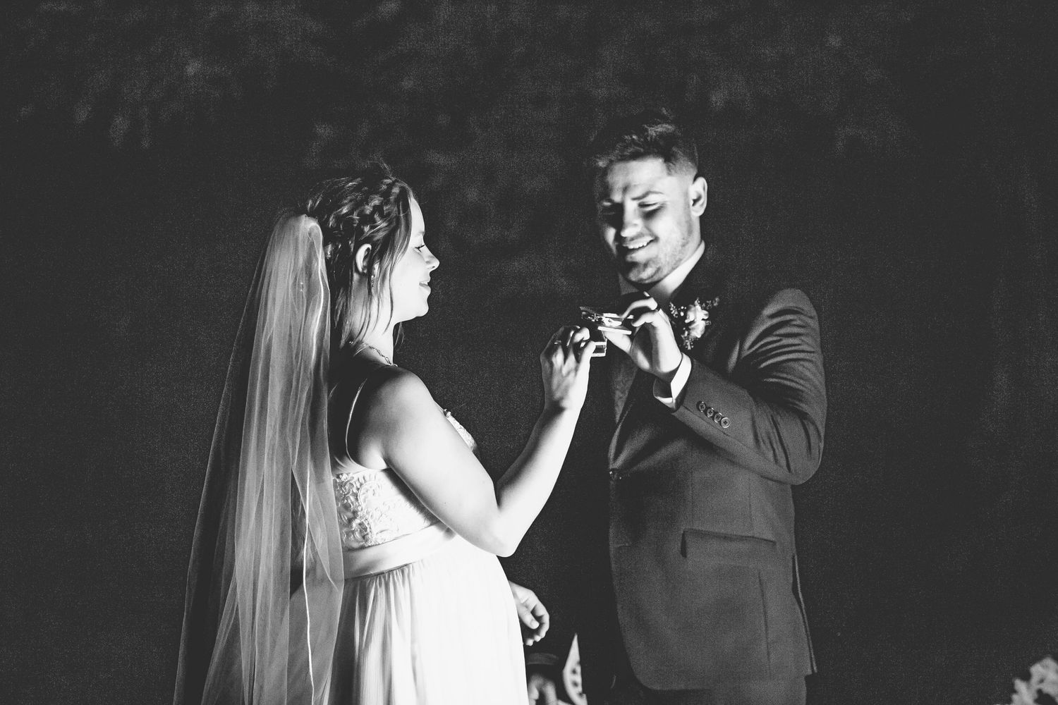 A couple dances together in dramatic black and white lighting at their wedding reception.