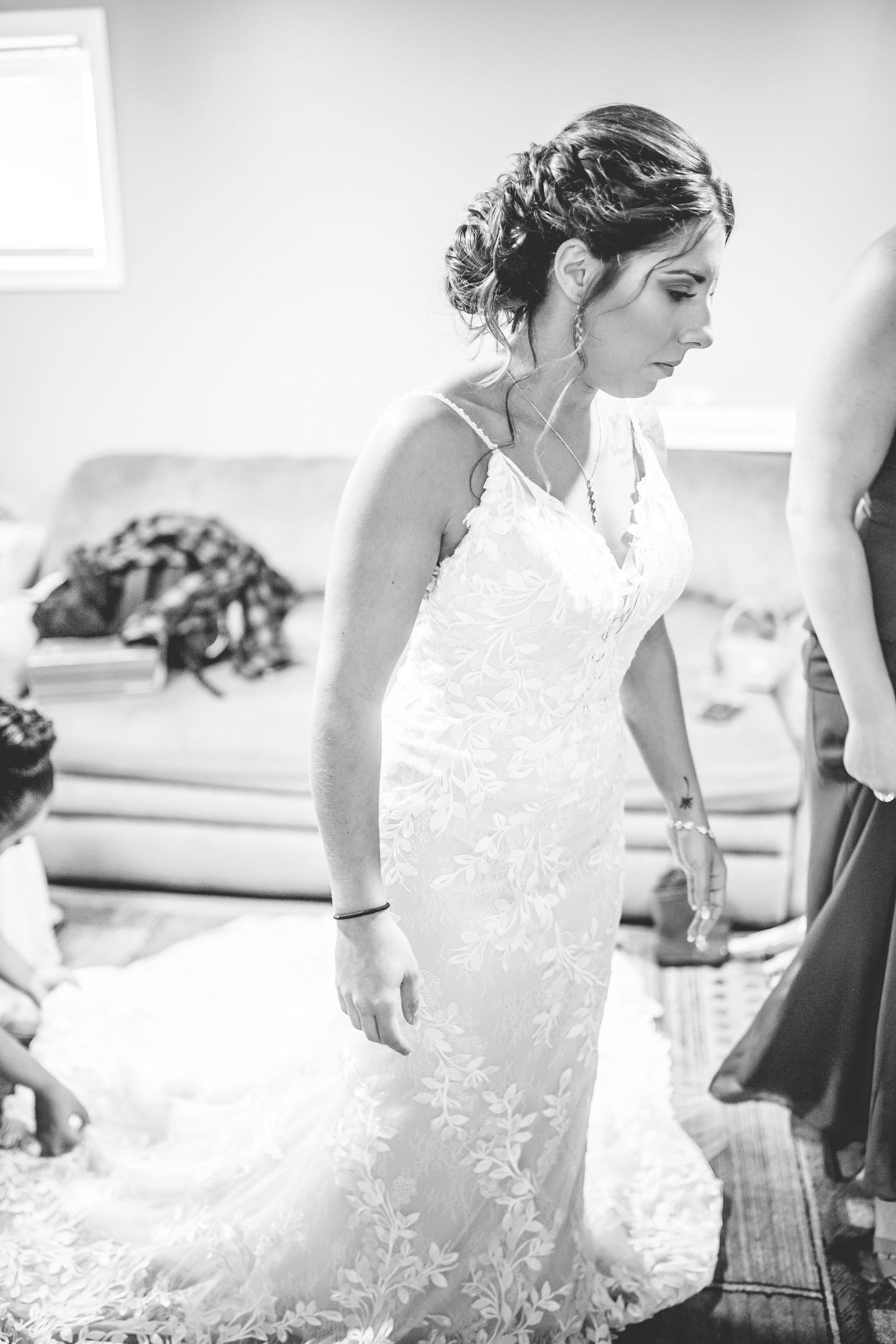 Black and white photos showing the process of putting on a lace wedding gown.
