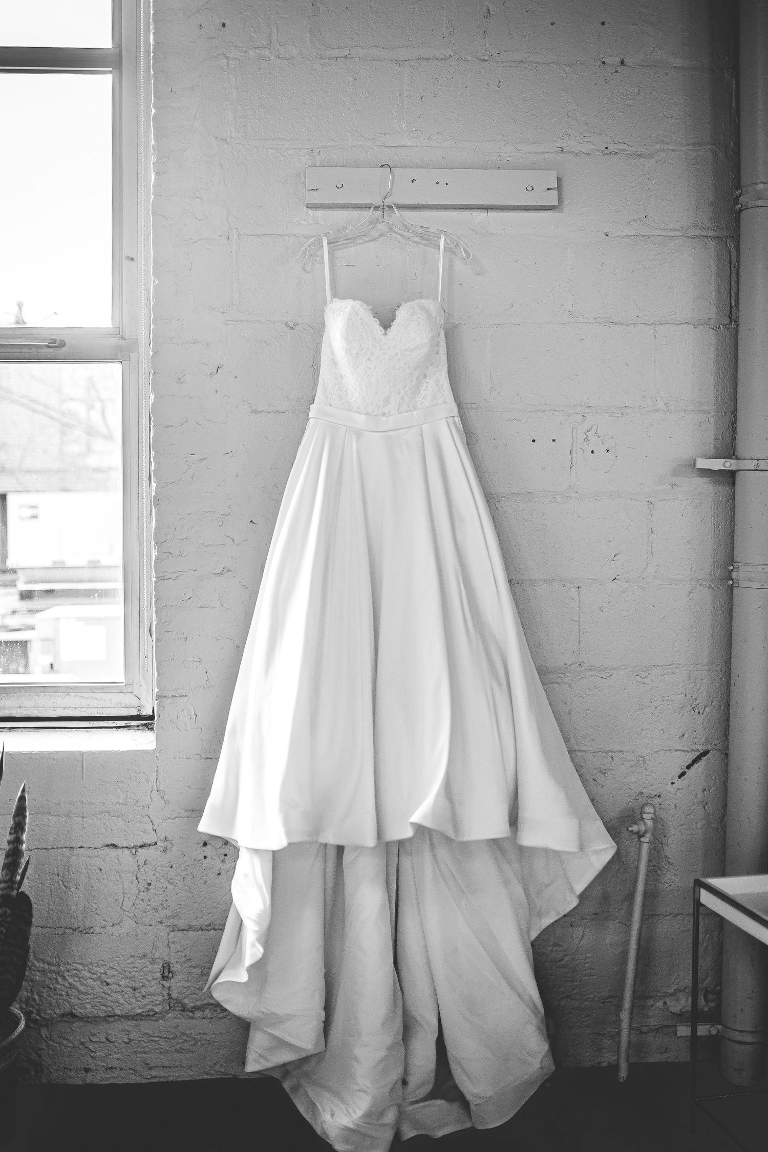 Wedding dress displayed in black and white against industrial windows.