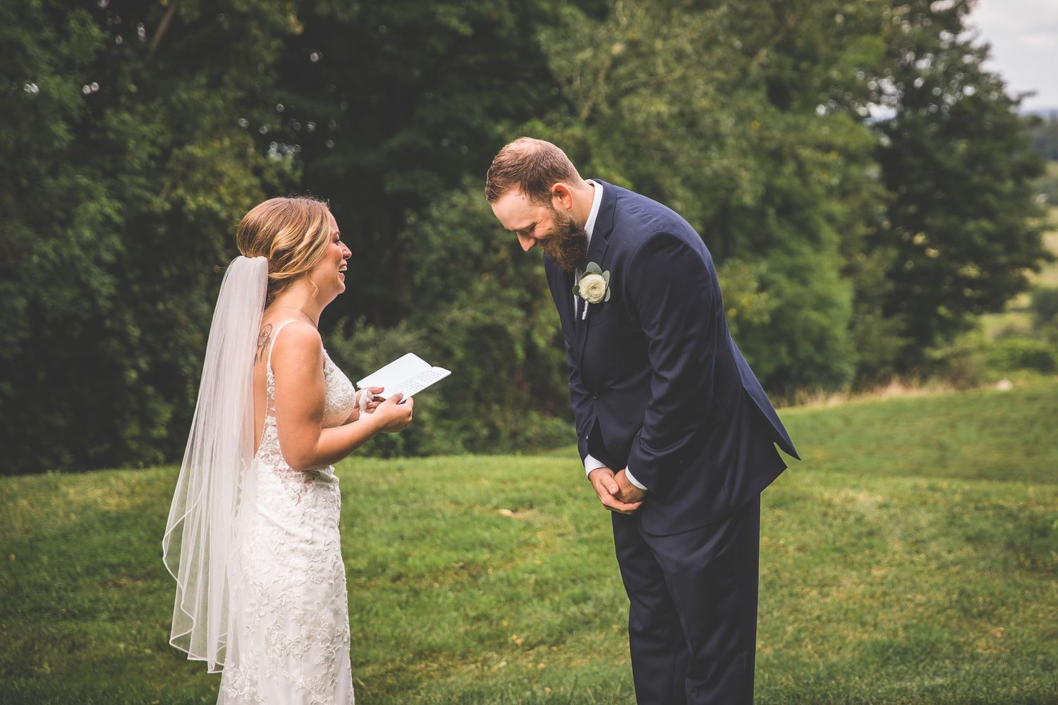 First look wedding moment captured in natural outdoor setting with trees and rolling hills.
