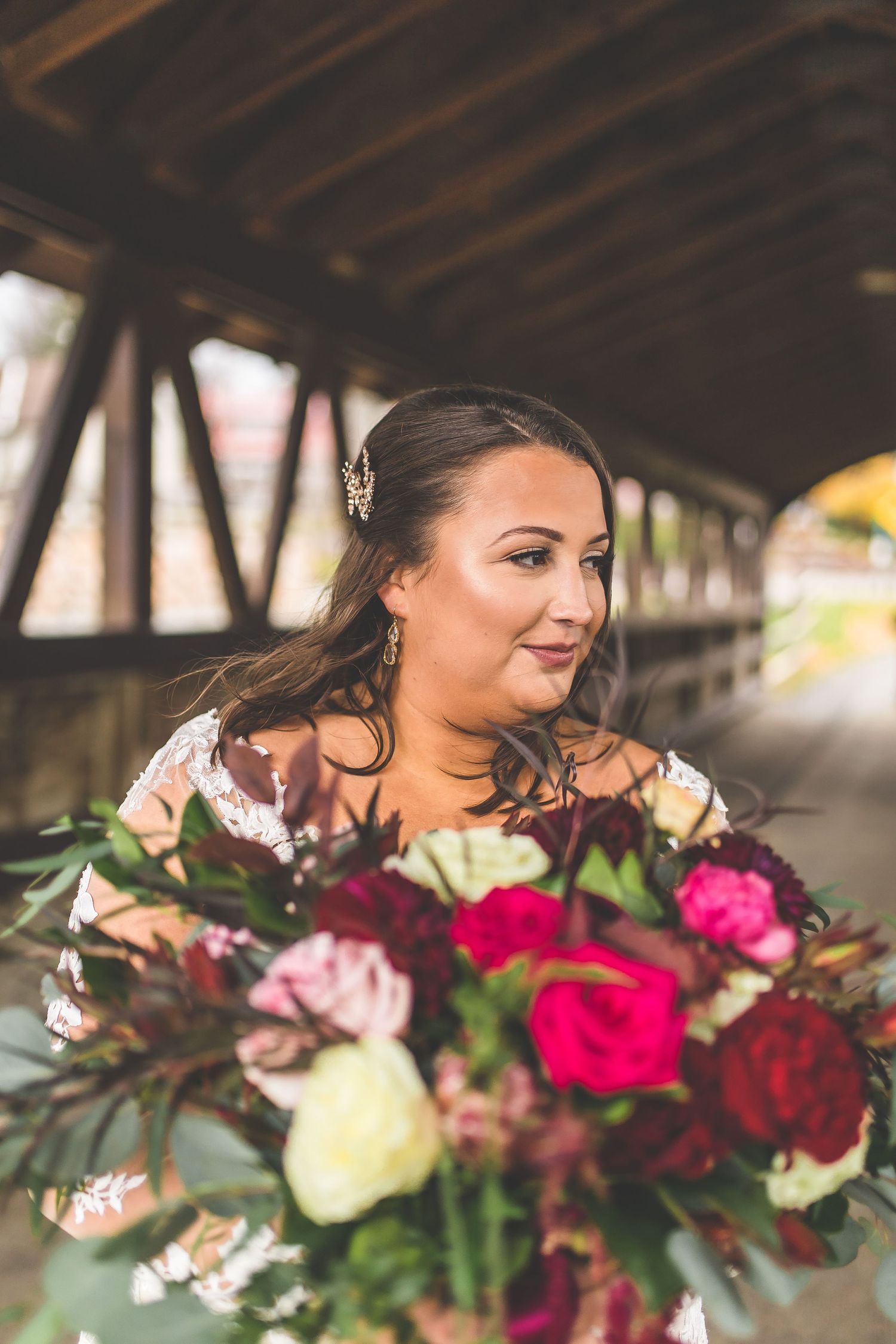 Close-up shots of bridal bouquet featuring deep red and pink roses with cascading greenery.