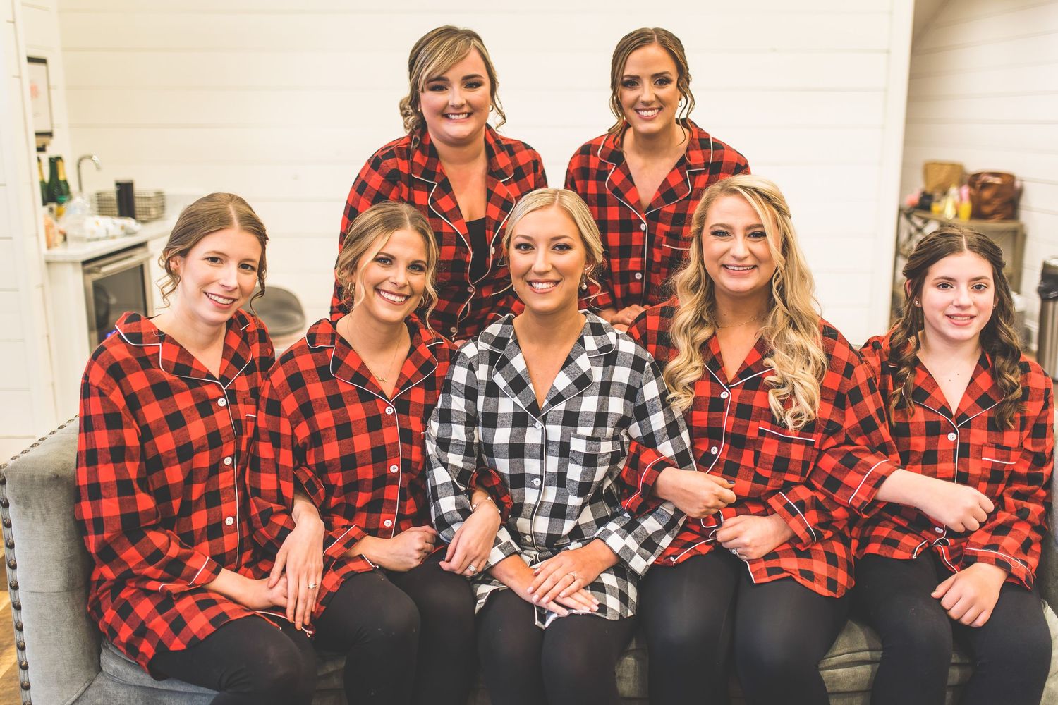 Group wearing matching red and black buffalo plaid shirts posing together.