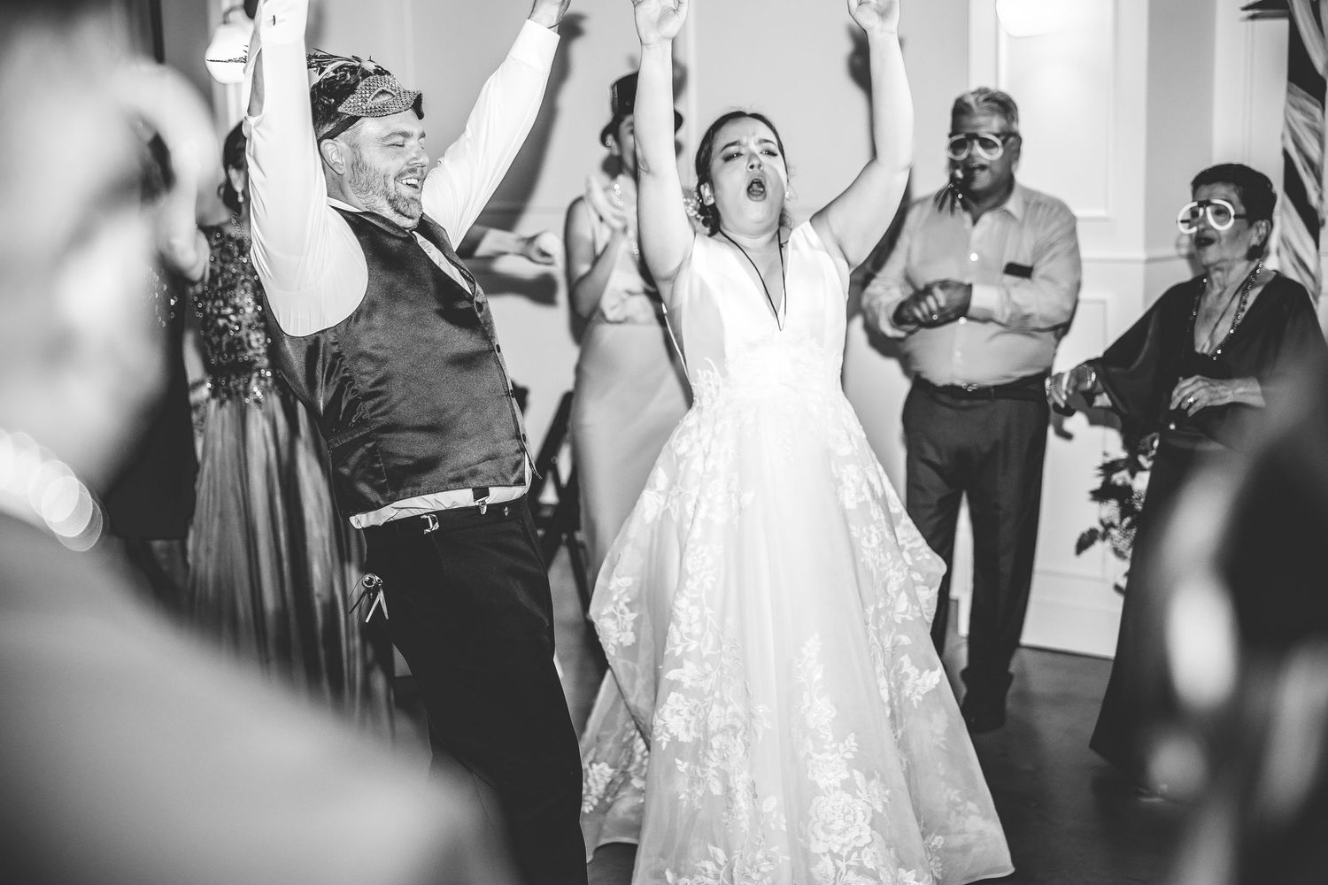 Black and white photo of wedding guests dancing and celebrating at reception.