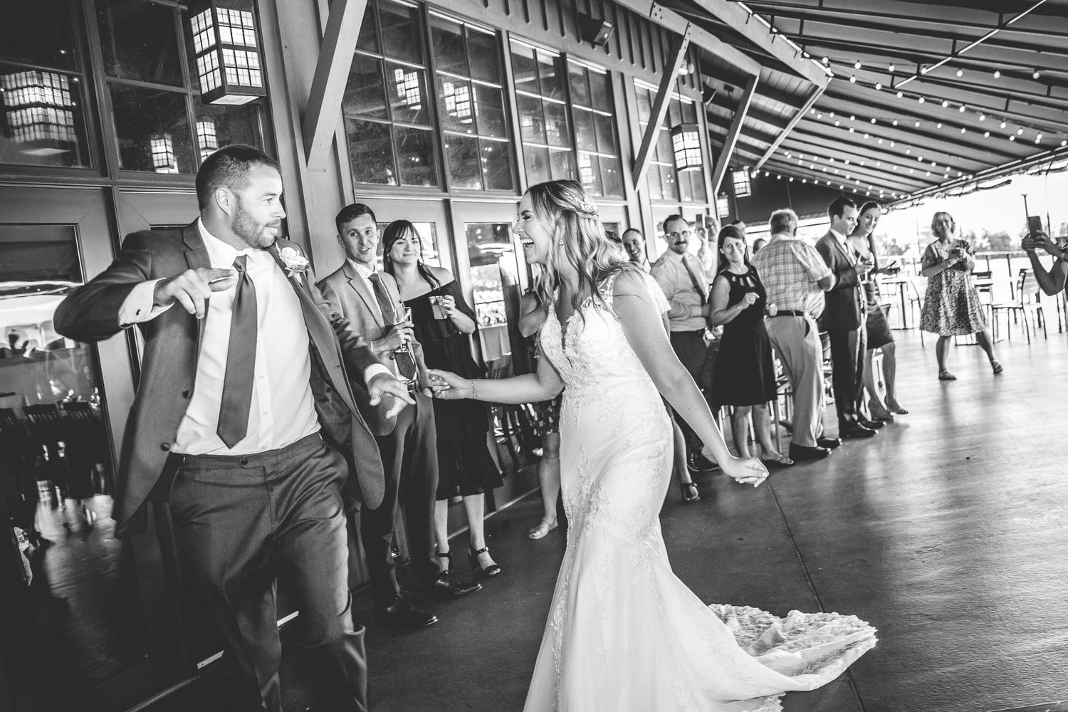 Black and white photo of wedding reception with couple dancing on covered outdoor deck.