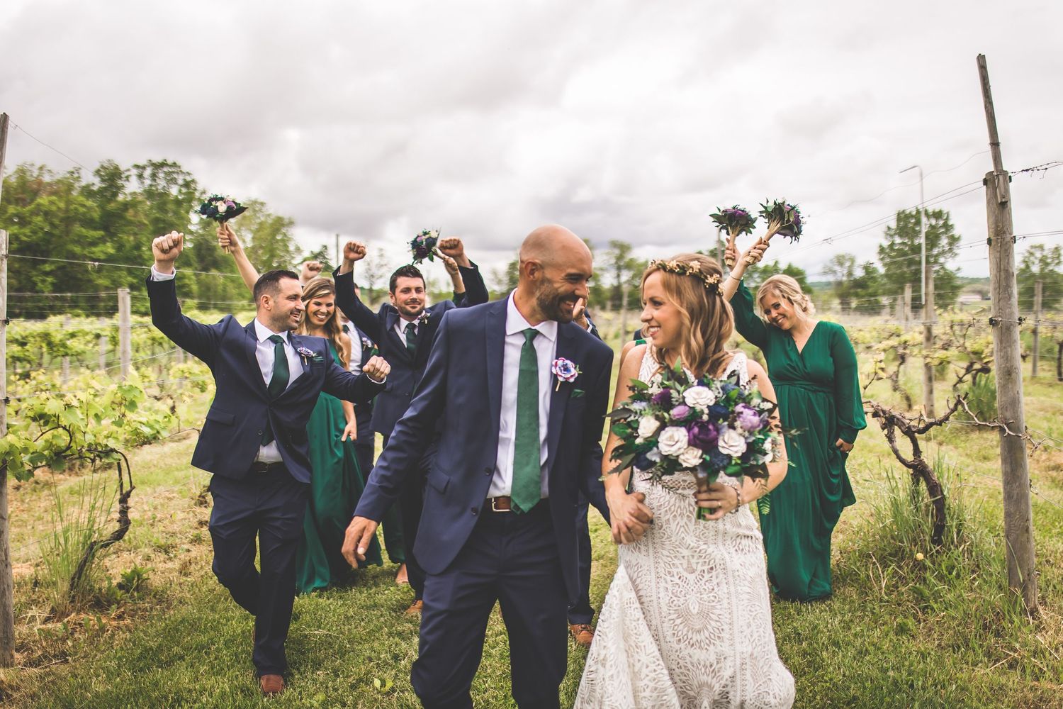 Wedding party celebrates with candid moments in outdoor vineyard setting.