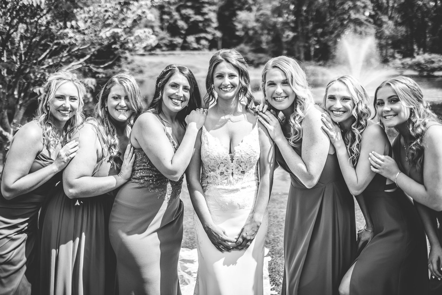 Black and white photo of wedding party members posing playfully outdoors.