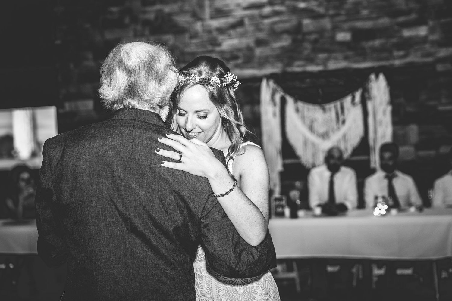 Black and white photo of couples dancing at a wedding reception under string lights.