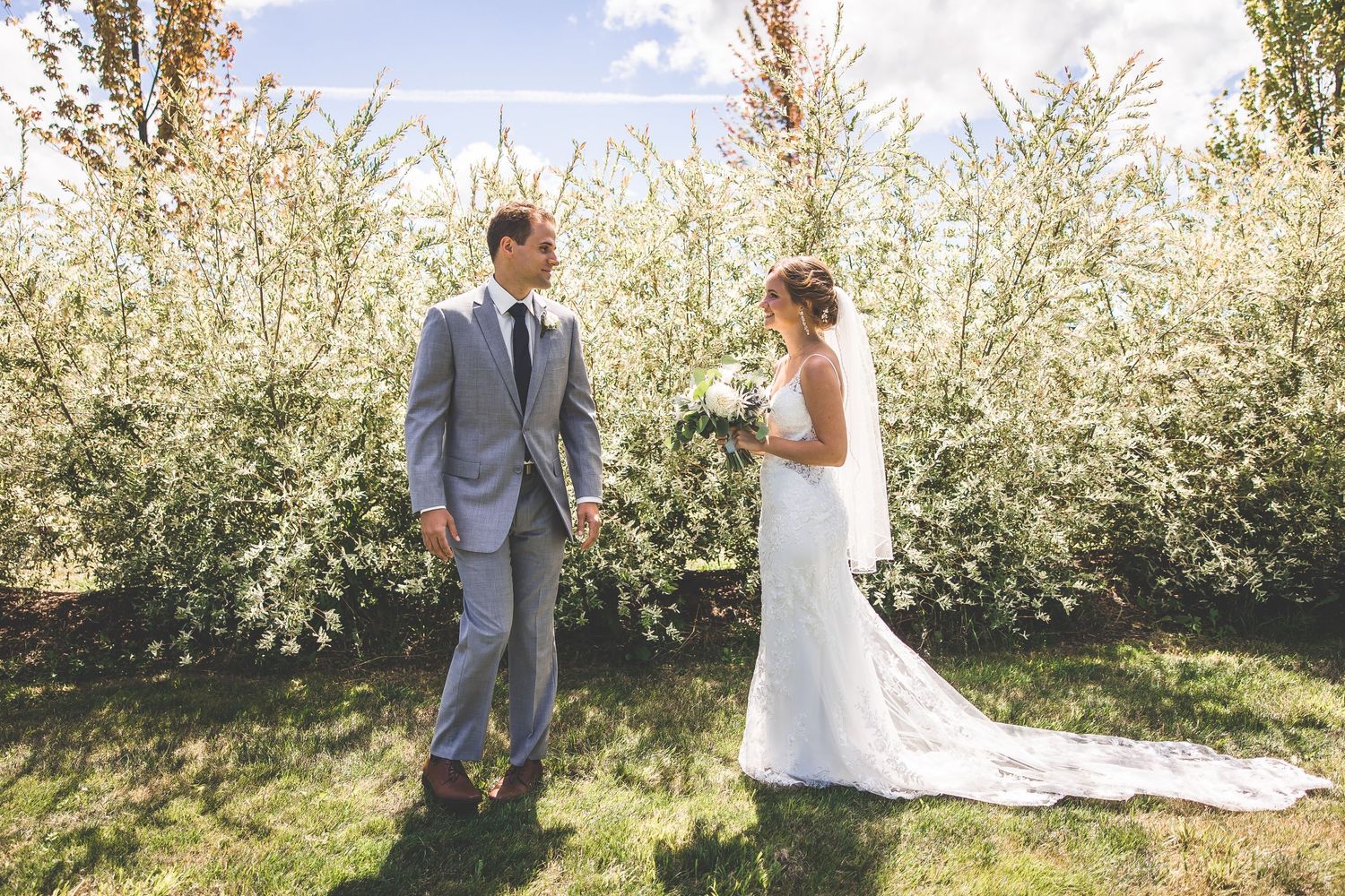 Bride and groom share intimate moment among blossoming spring trees.