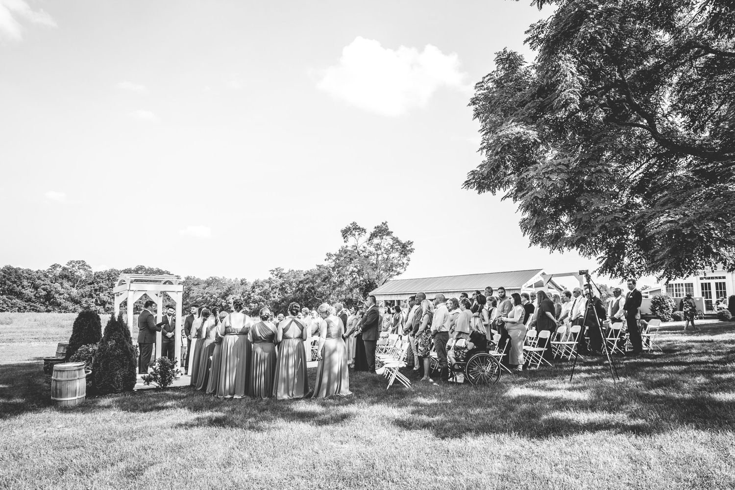 Black and white panoramic view of an outdoor wedding ceremony with guests seated.