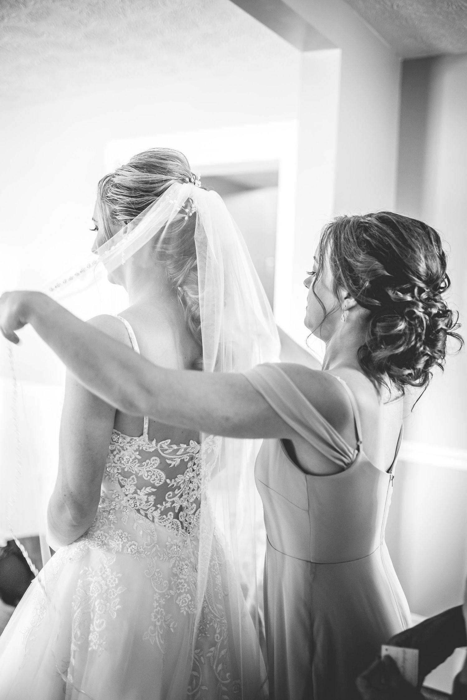 Black and white photo of wedding dress preparation with elegant lace details.