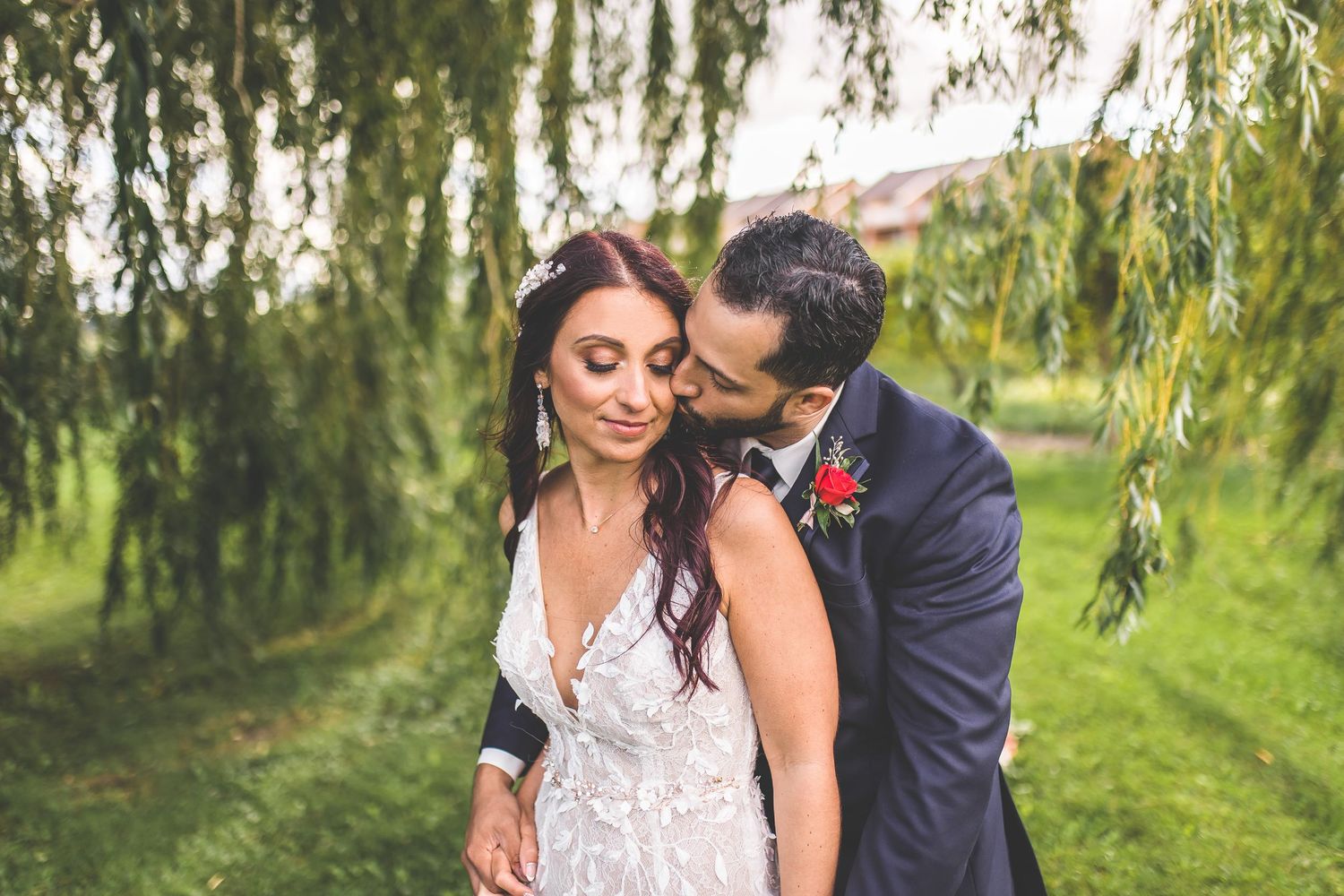 Romantic outdoor portrait under weeping willow trees in a garden setting.