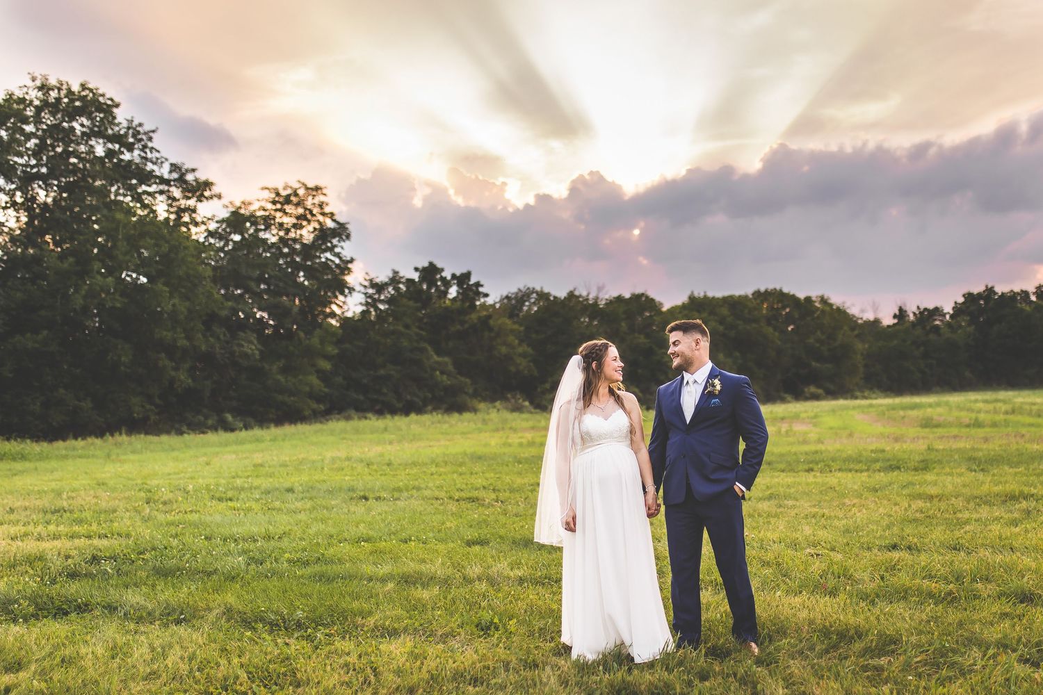 Sunset wedding photos in a golden meadow with dramatic sky backdrop.