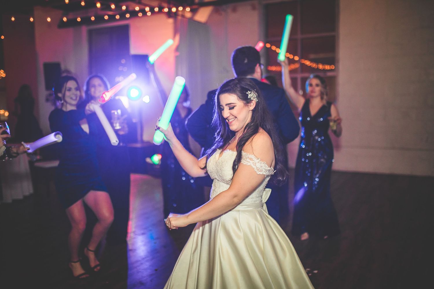 Wedding reception dance floor with colorful lighting and guests celebrating.