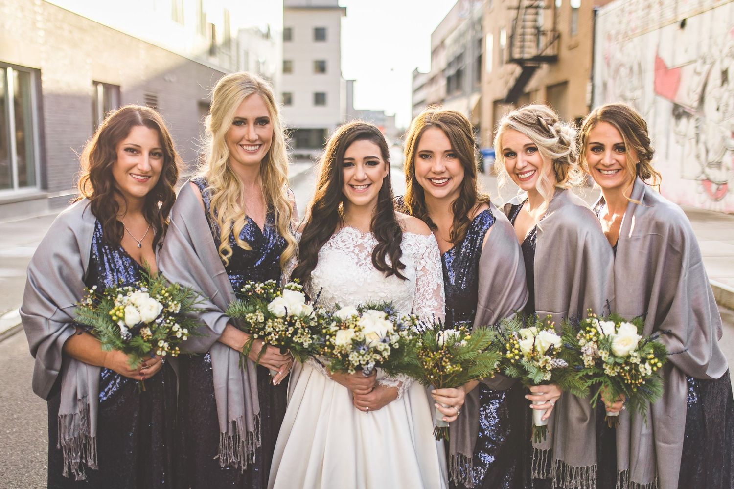 Wedding party wearing coordinated gray accessories poses outdoors.