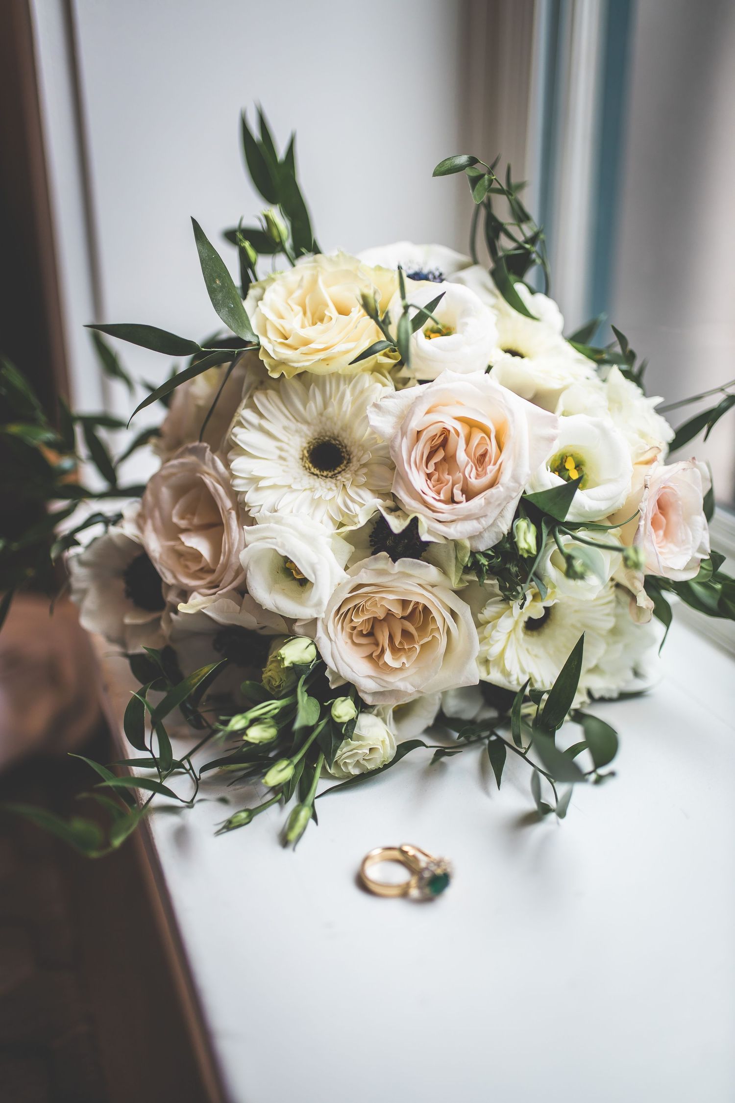 Elegant floral arrangement with white and blush roses displayed on a light surface.