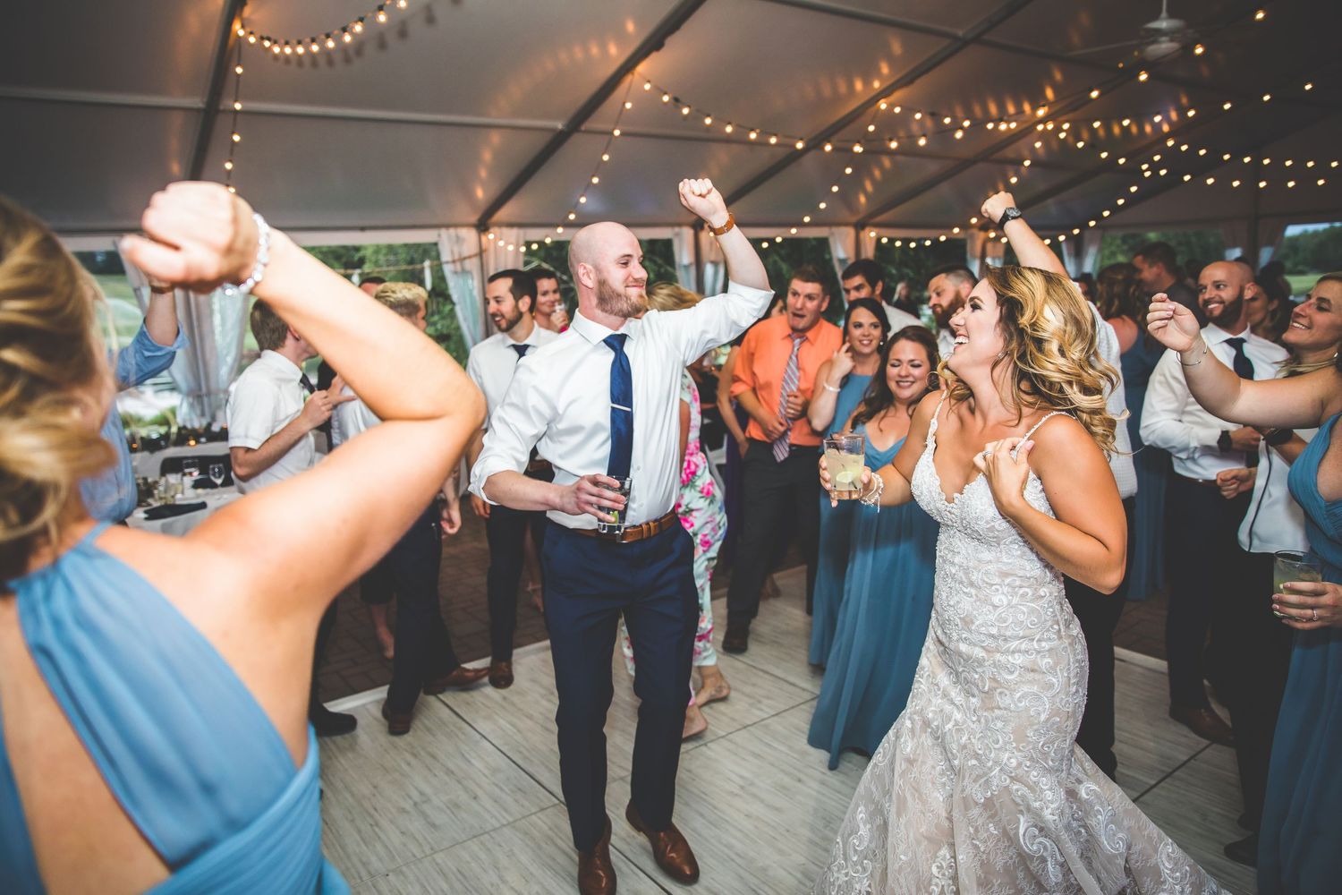 Wedding reception party with guests dancing under string lights.