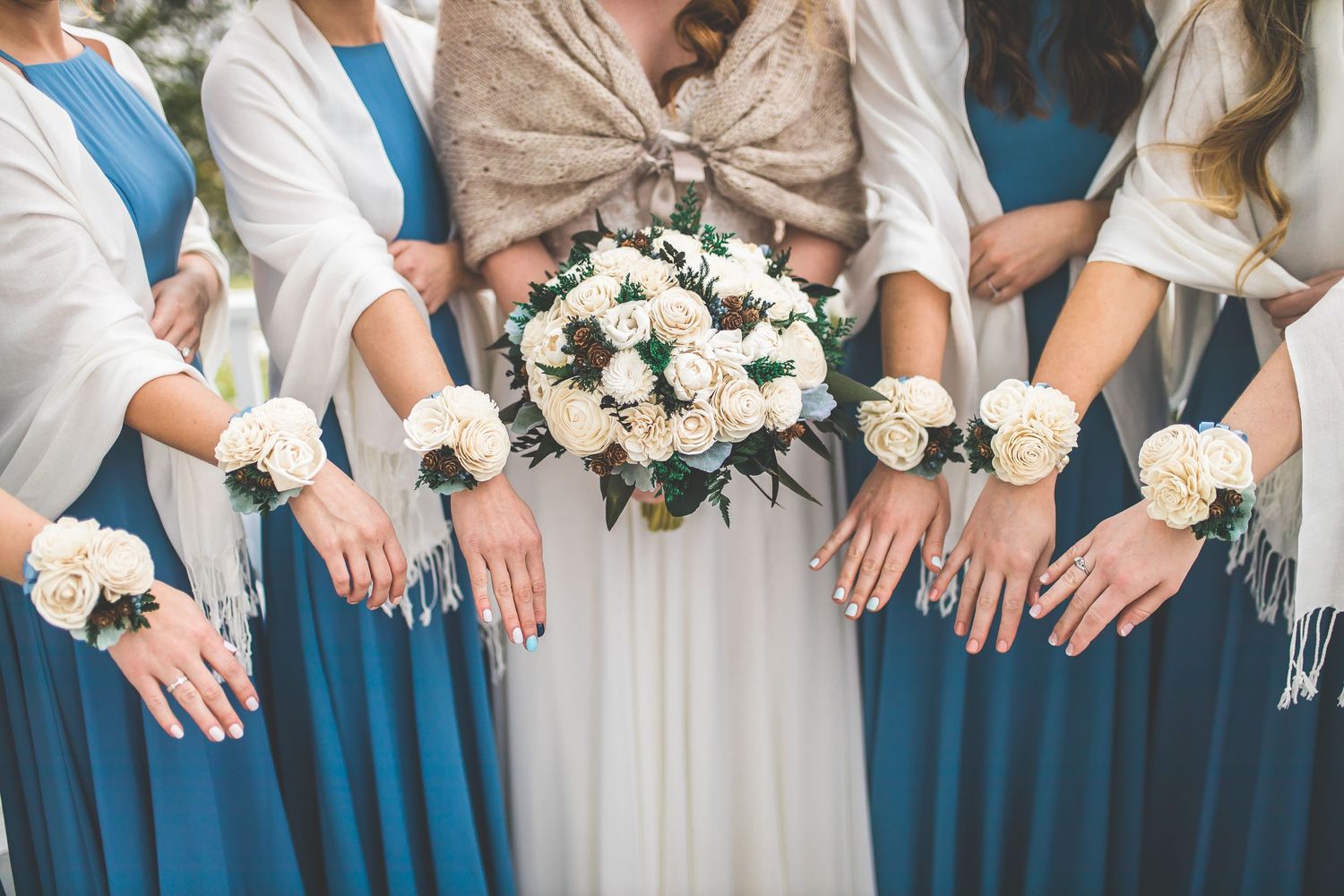 Wedding party in teal blue dresses and black suits pose together on a white columned porch.