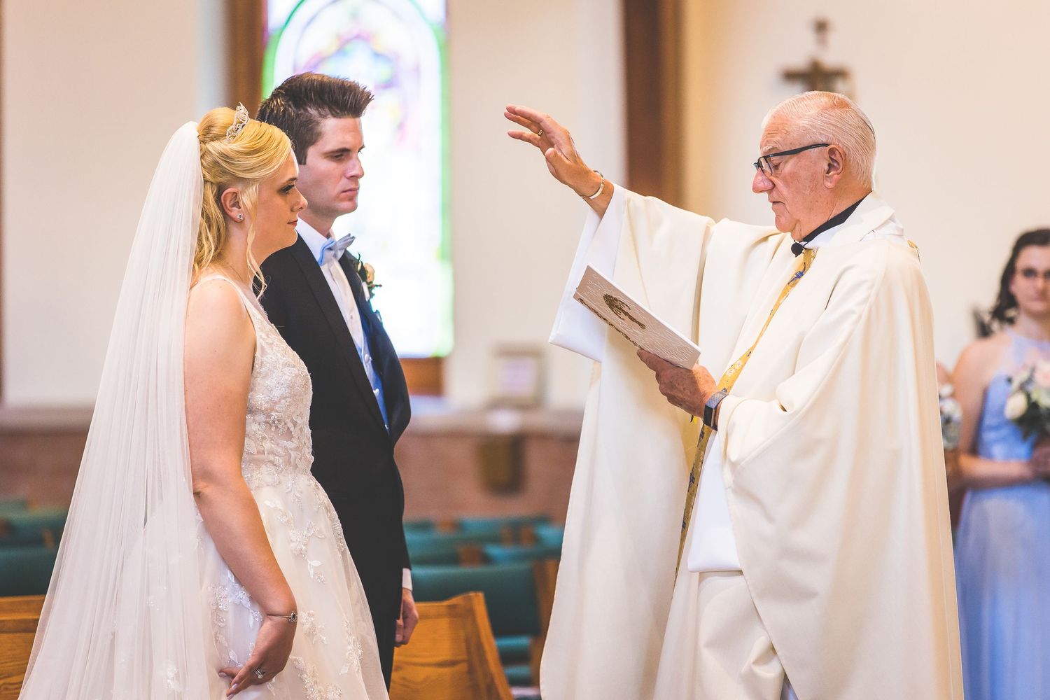 Wedding ceremony participants standing at altar in church.