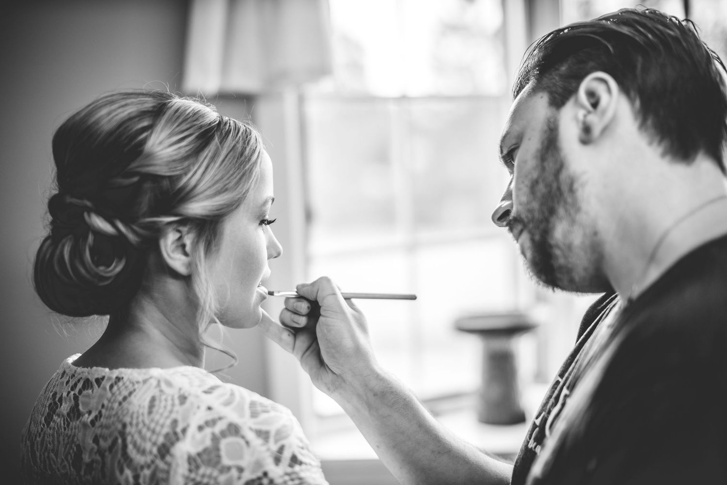 Black and white intimate wedding preparation moments captured in natural window light.