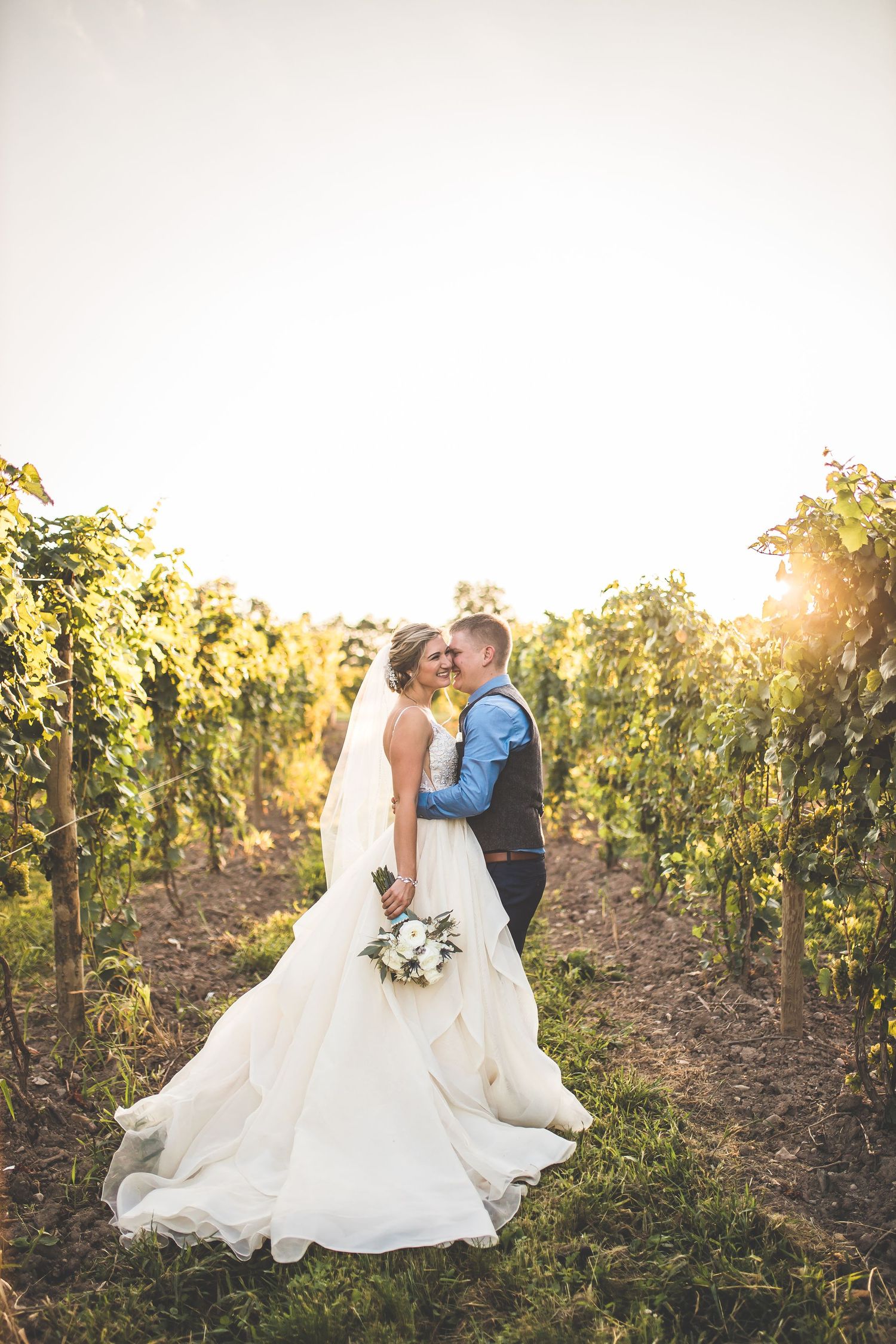 Romantic sunset photos in vineyard with wedding dress flowing in evening light.