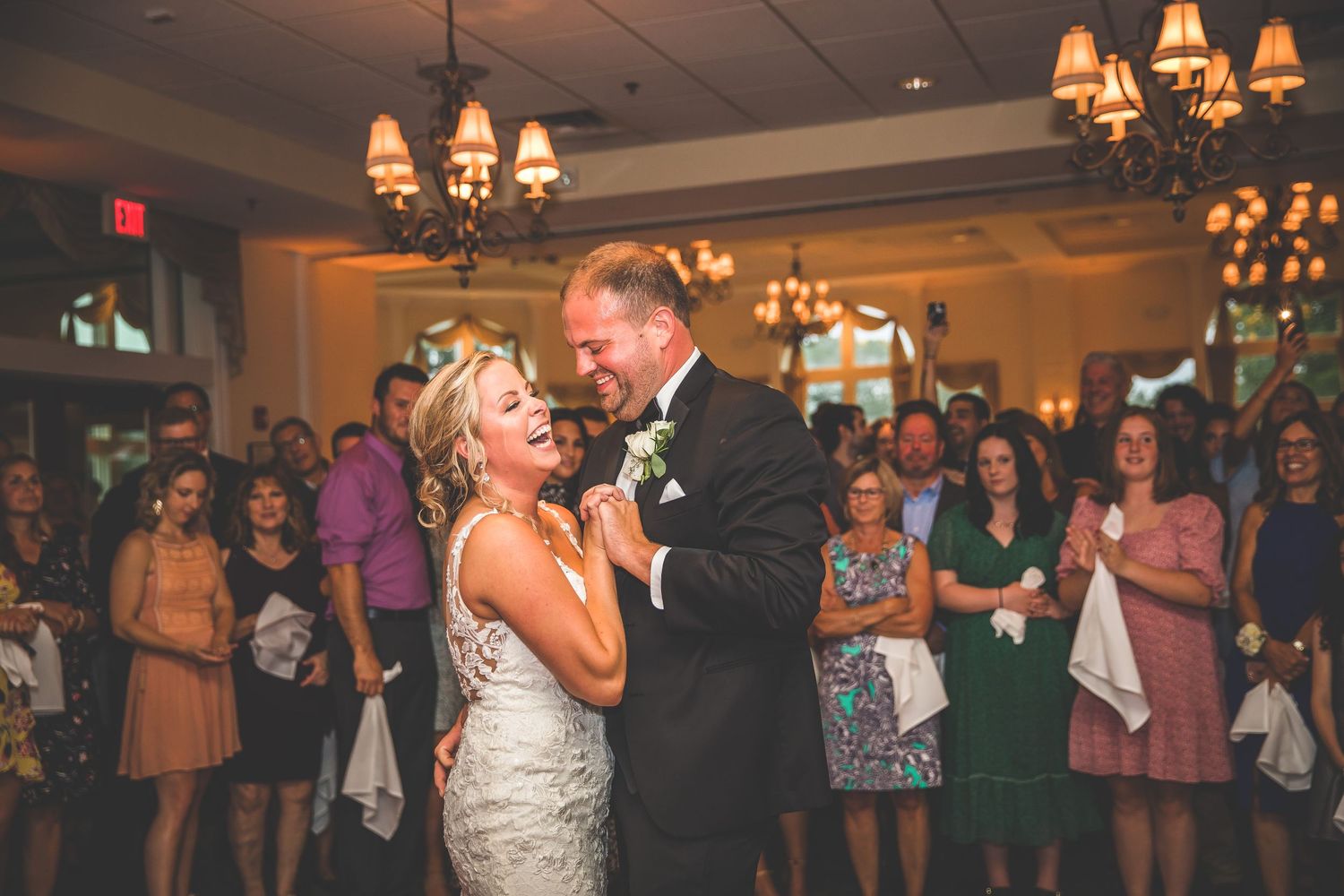 Couple dances romantically while wedding guests watch from the reception dance floor.