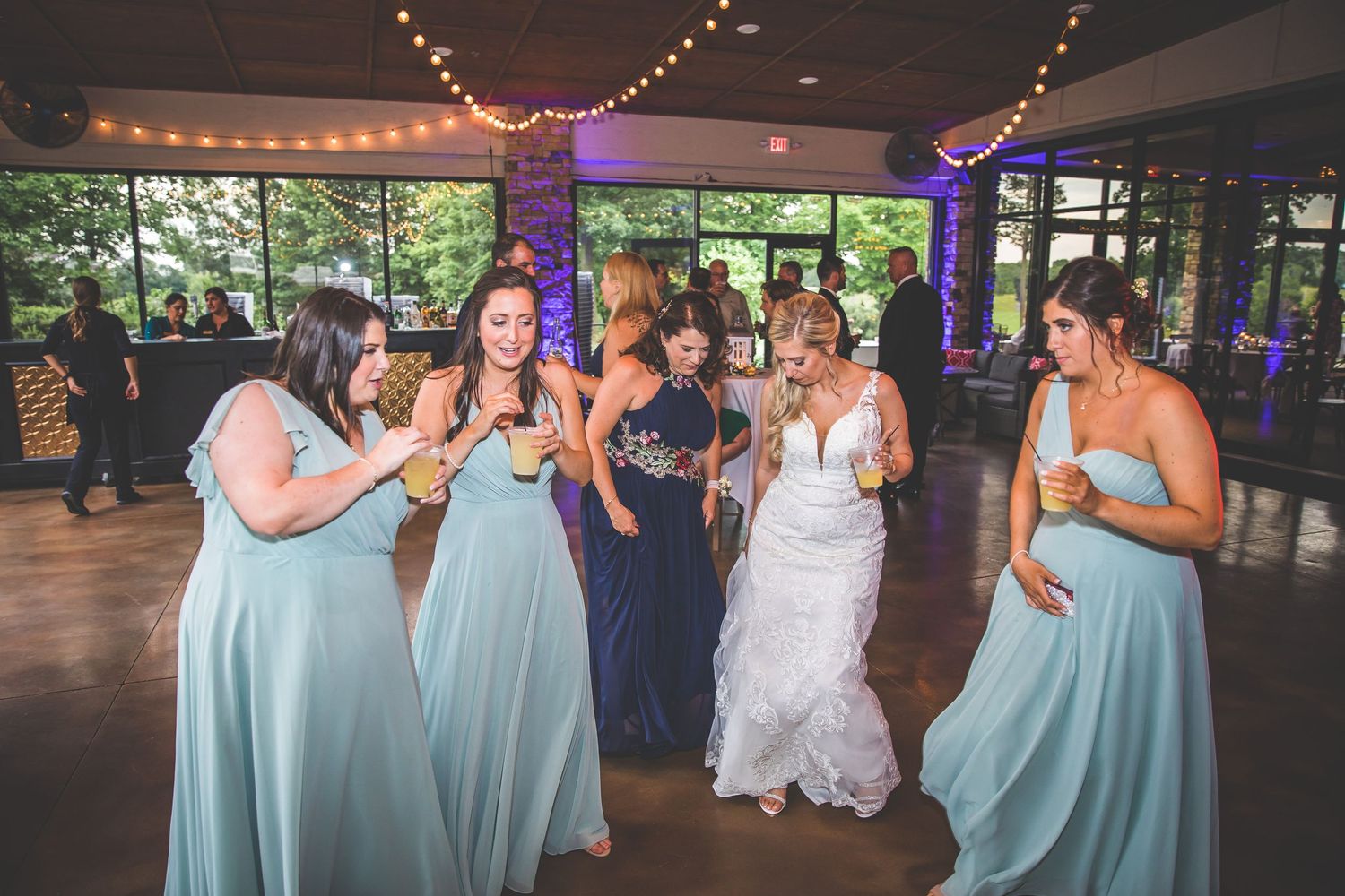 Wedding party watching the couple dance in a beautifully lit reception hall.