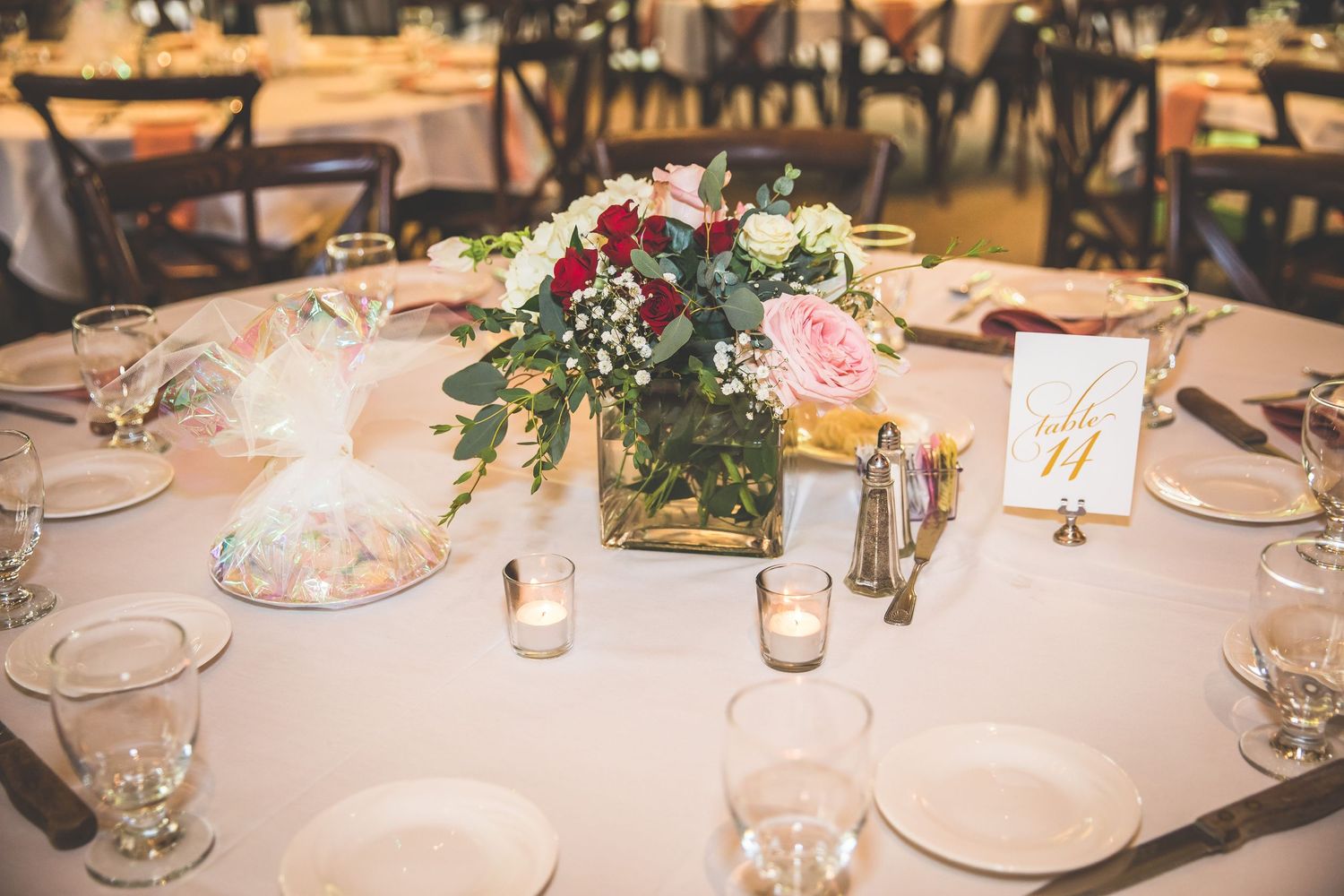 An elegant wedding table setting with floral centerpiece, glassware and table numbers.