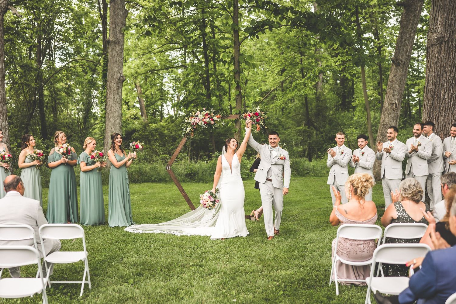 Wedding ceremony setup in a lush green forest with white chairs arranged in rows for guests.