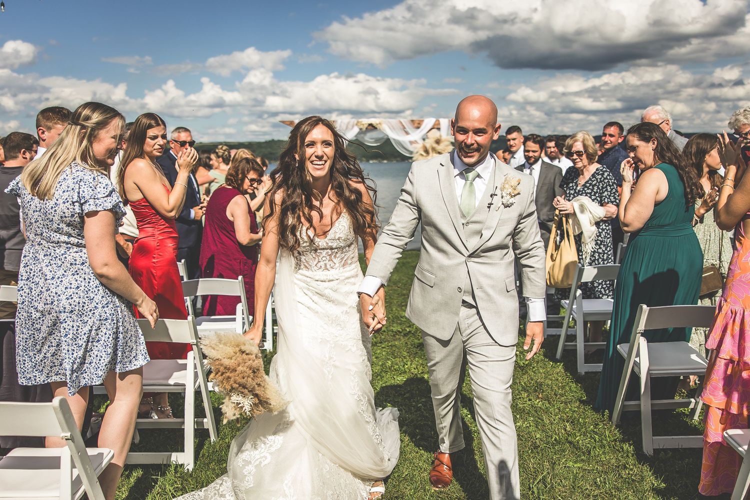Joyful celebration at a waterfront wedding with guests cheering during the recessional.
