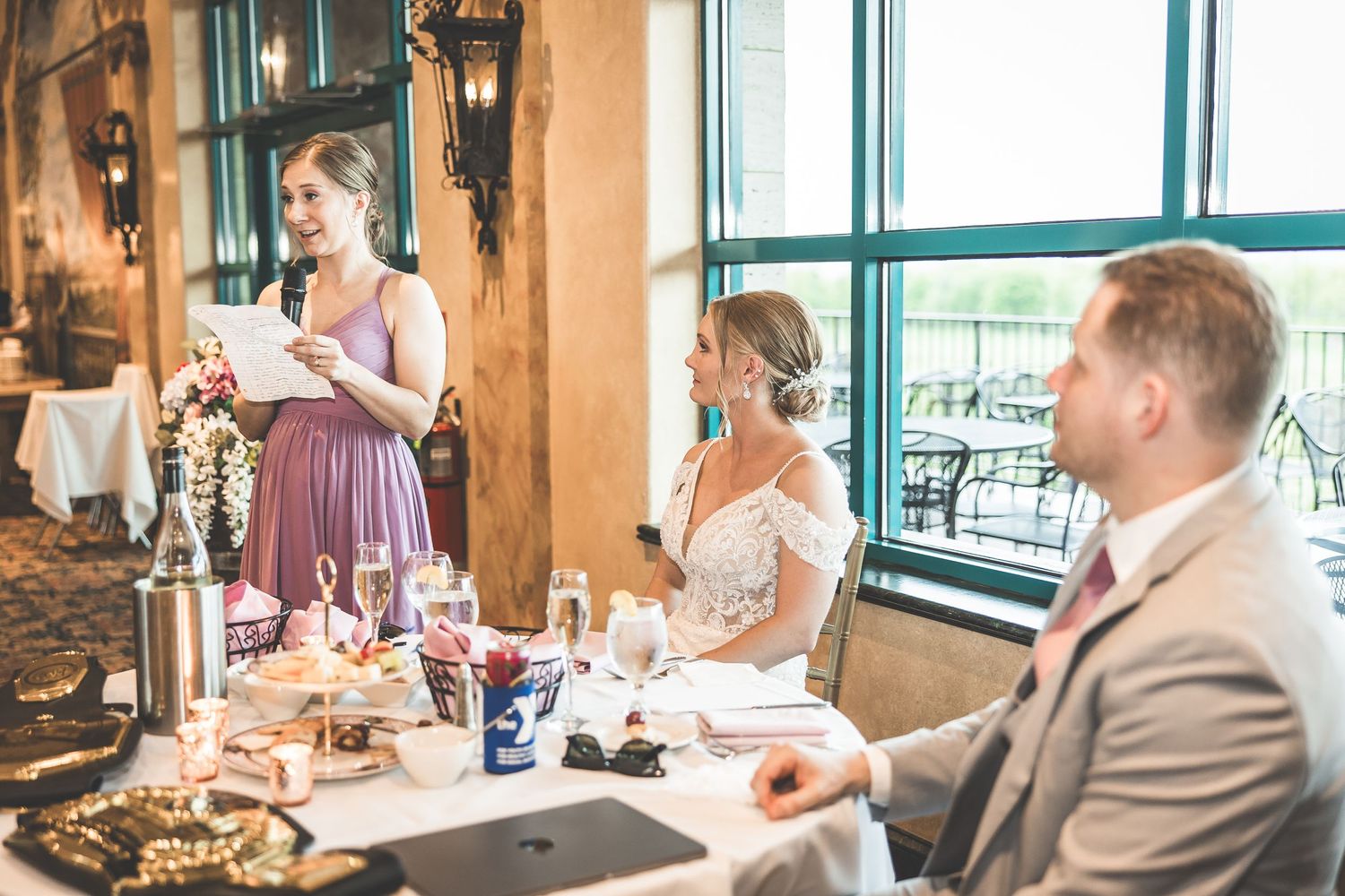 Wedding reception scene with natural light streaming through large turquoise-framed windows.