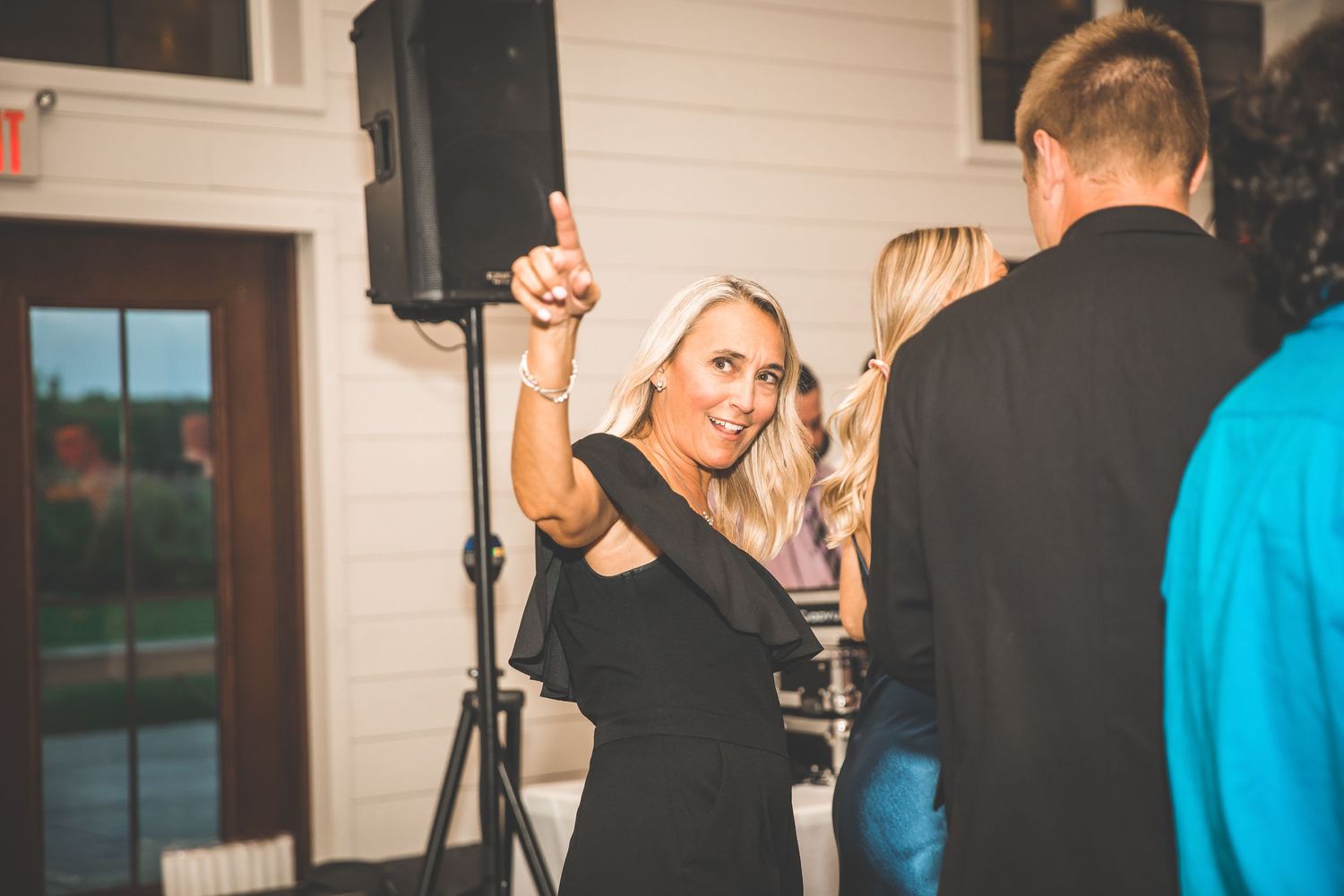 A guest dances and raises her hand during a lively wedding reception party.