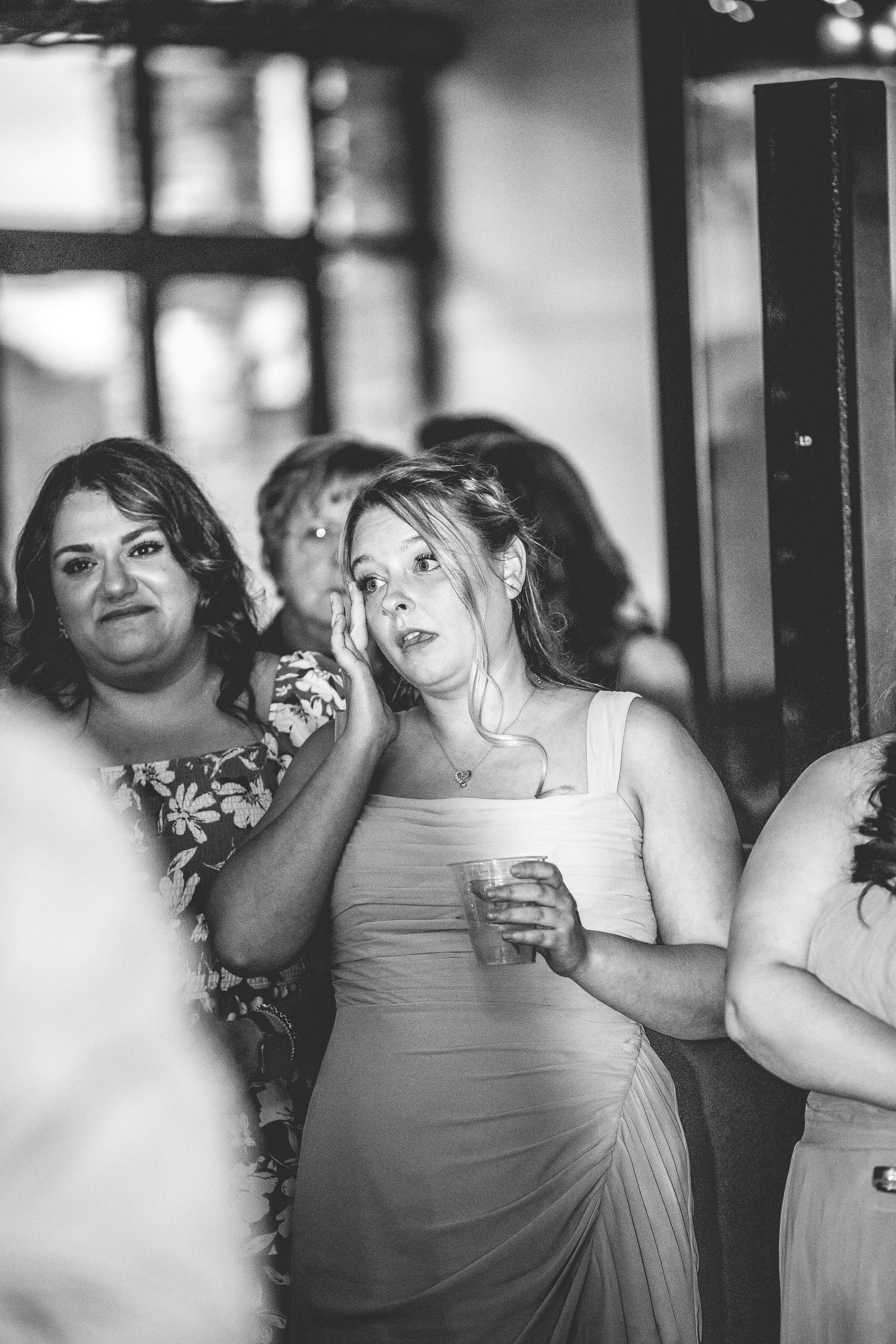 Bridesmaids in light colored dresses share emotional moments during wedding festivities.