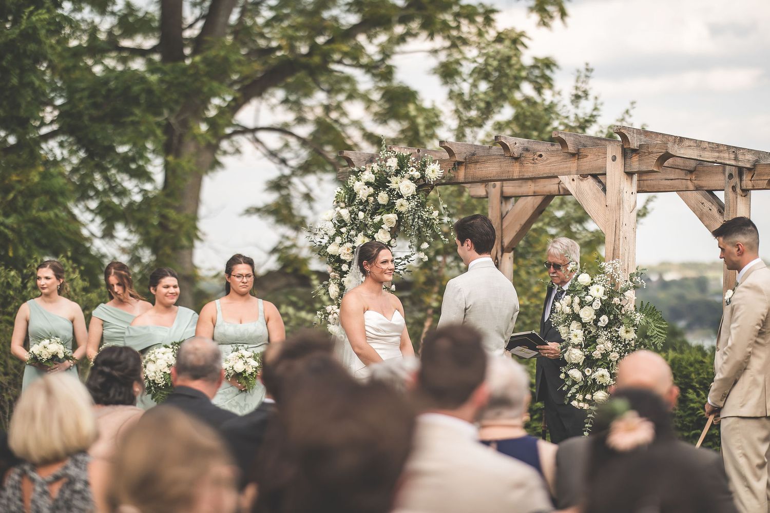 Outdoor wedding ceremony setup with wooden arch and white floral decorations.