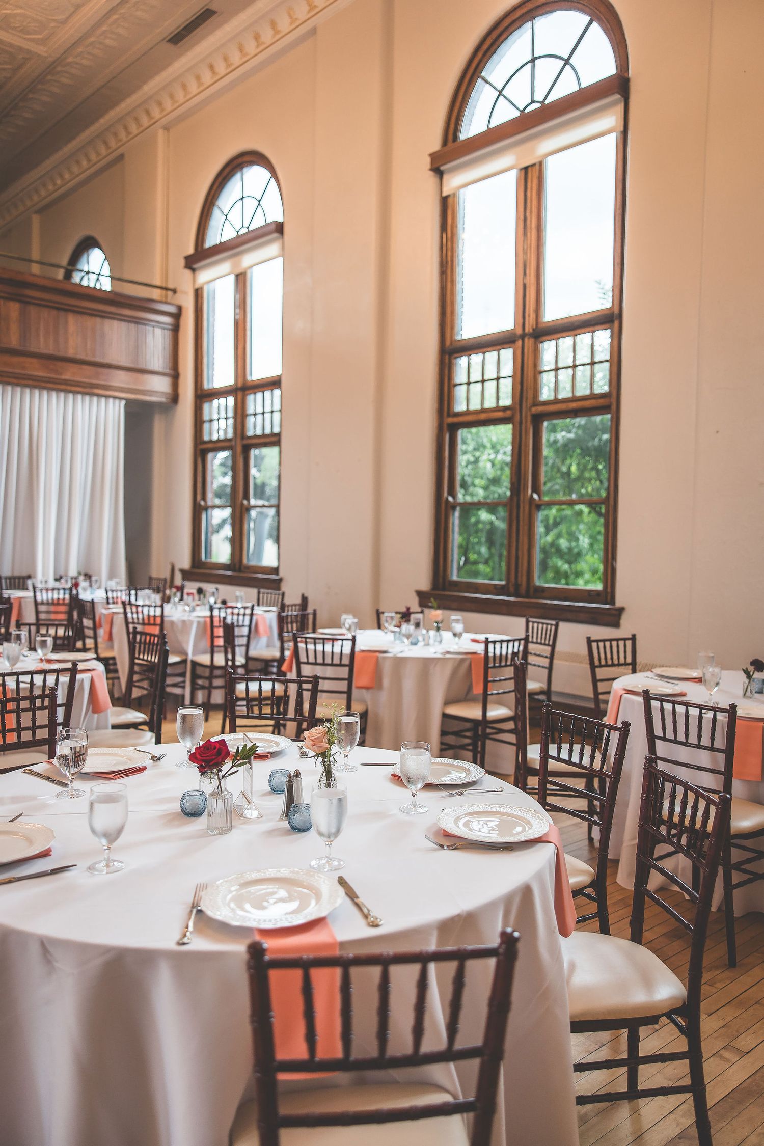 Elegant wedding reception hall with arched windows, white tablecloths and chiavari chairs.