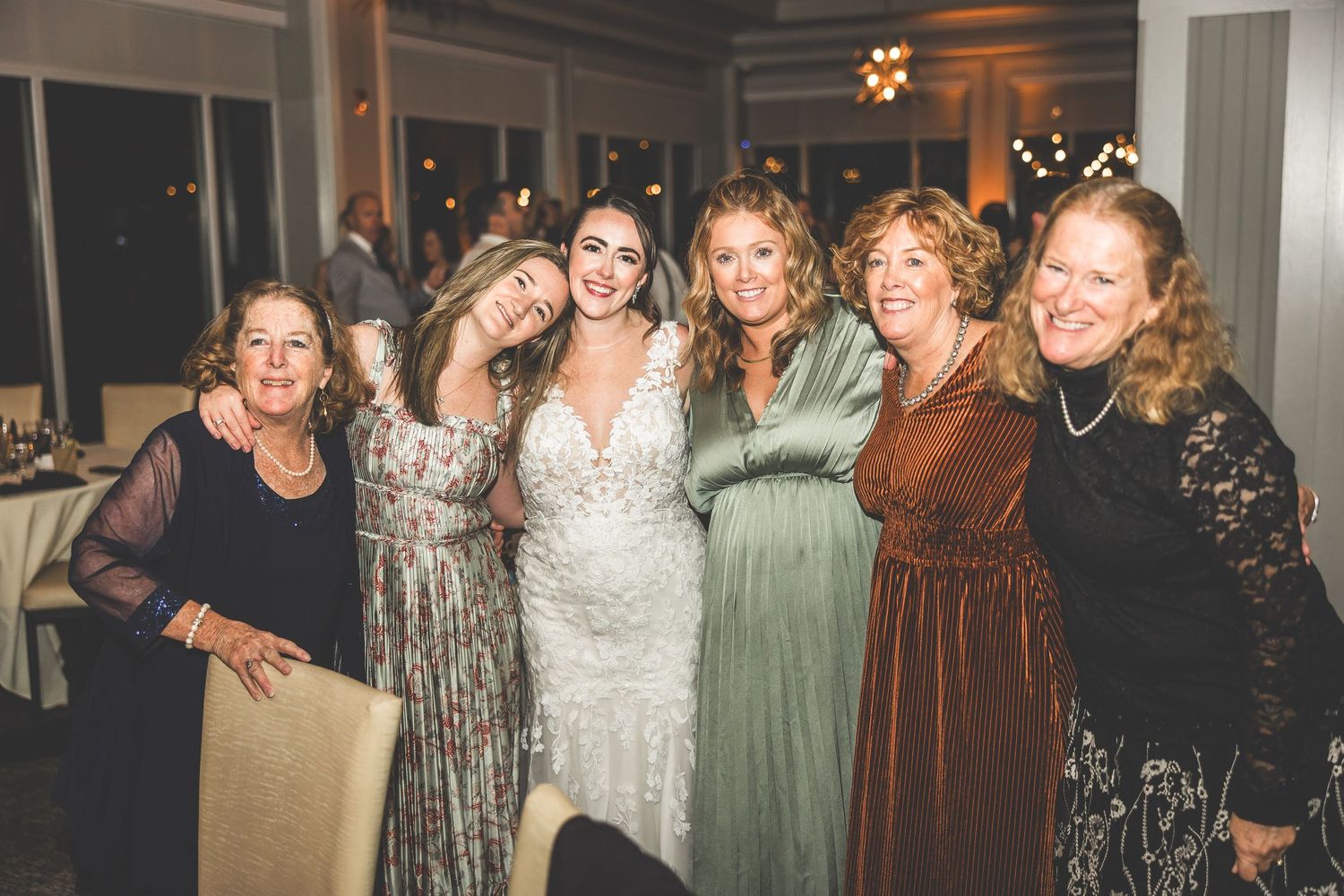 Group of wedding guests posing together during an indoor evening celebration.