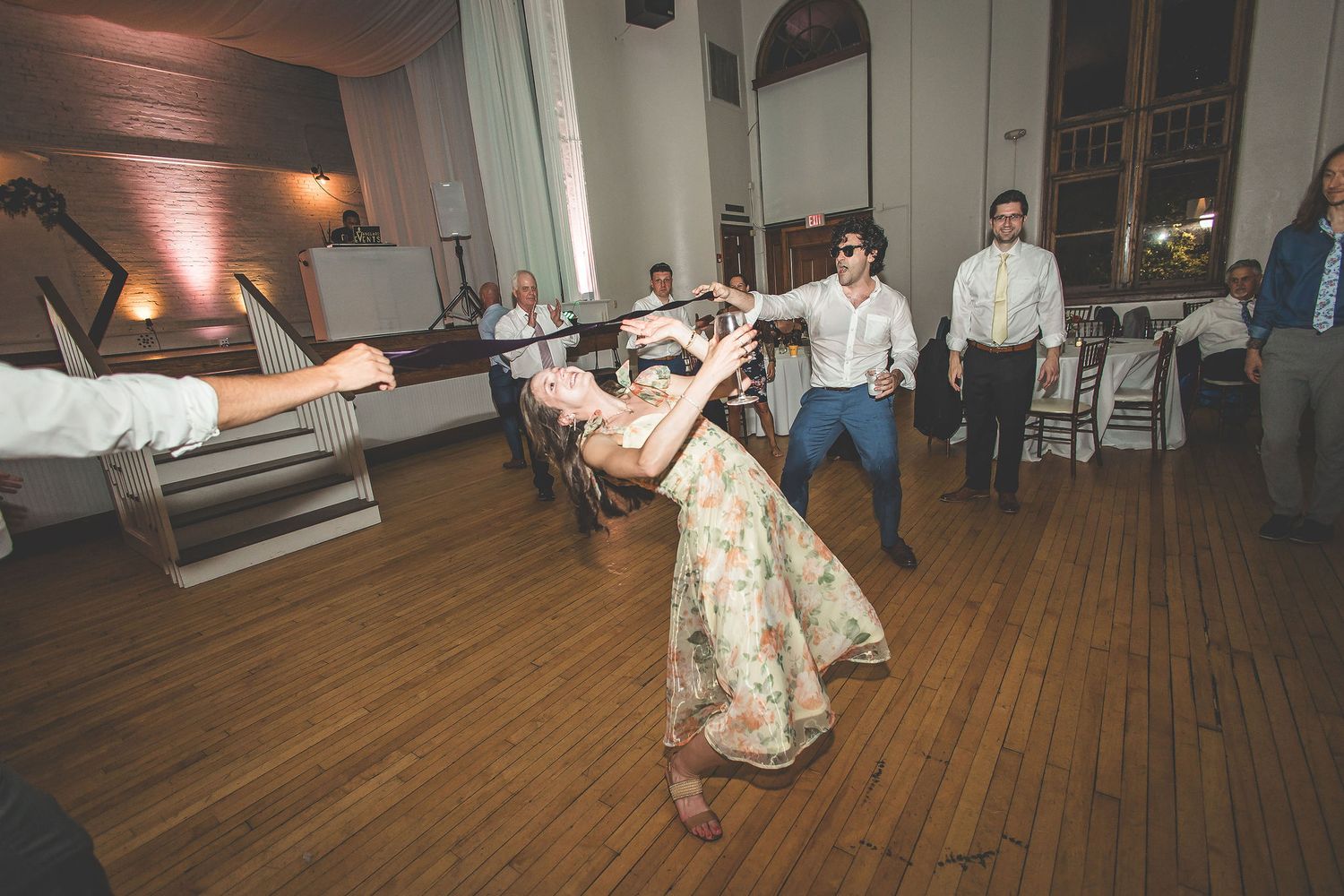 Couples dancing at a wedding reception in a classic ballroom with hardwood floors and wall sconces.