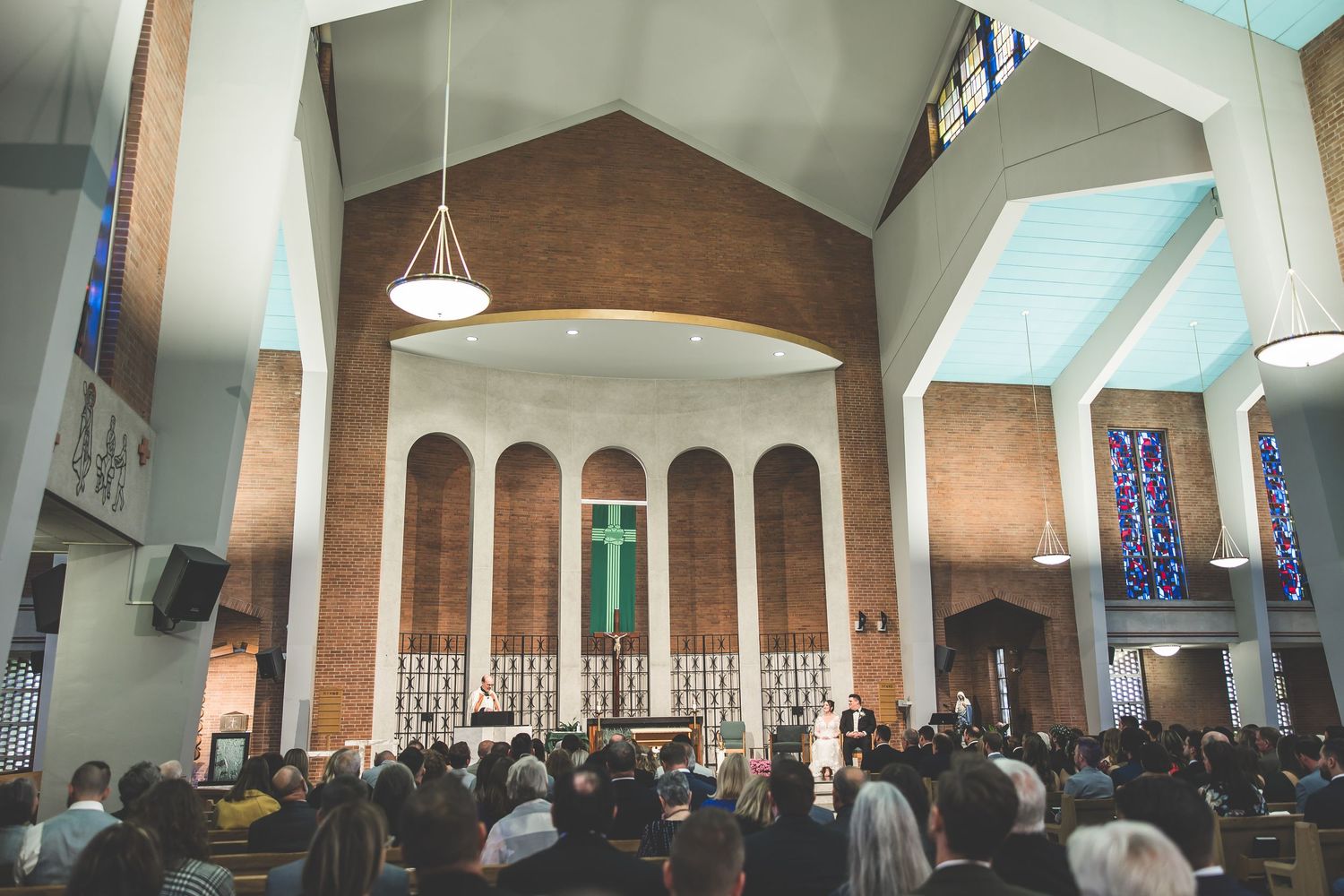 Panoramic view of a church sanctuary with vaulted ceilings and stained glass windows.