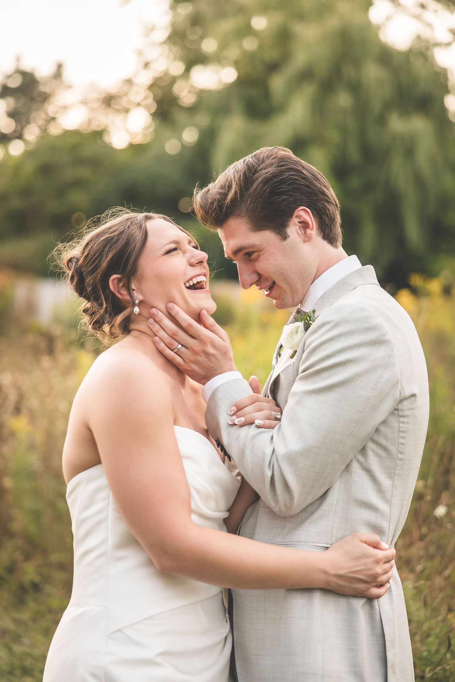 Joyful couple shares emotional moment during outdoor wedding photoshoot.