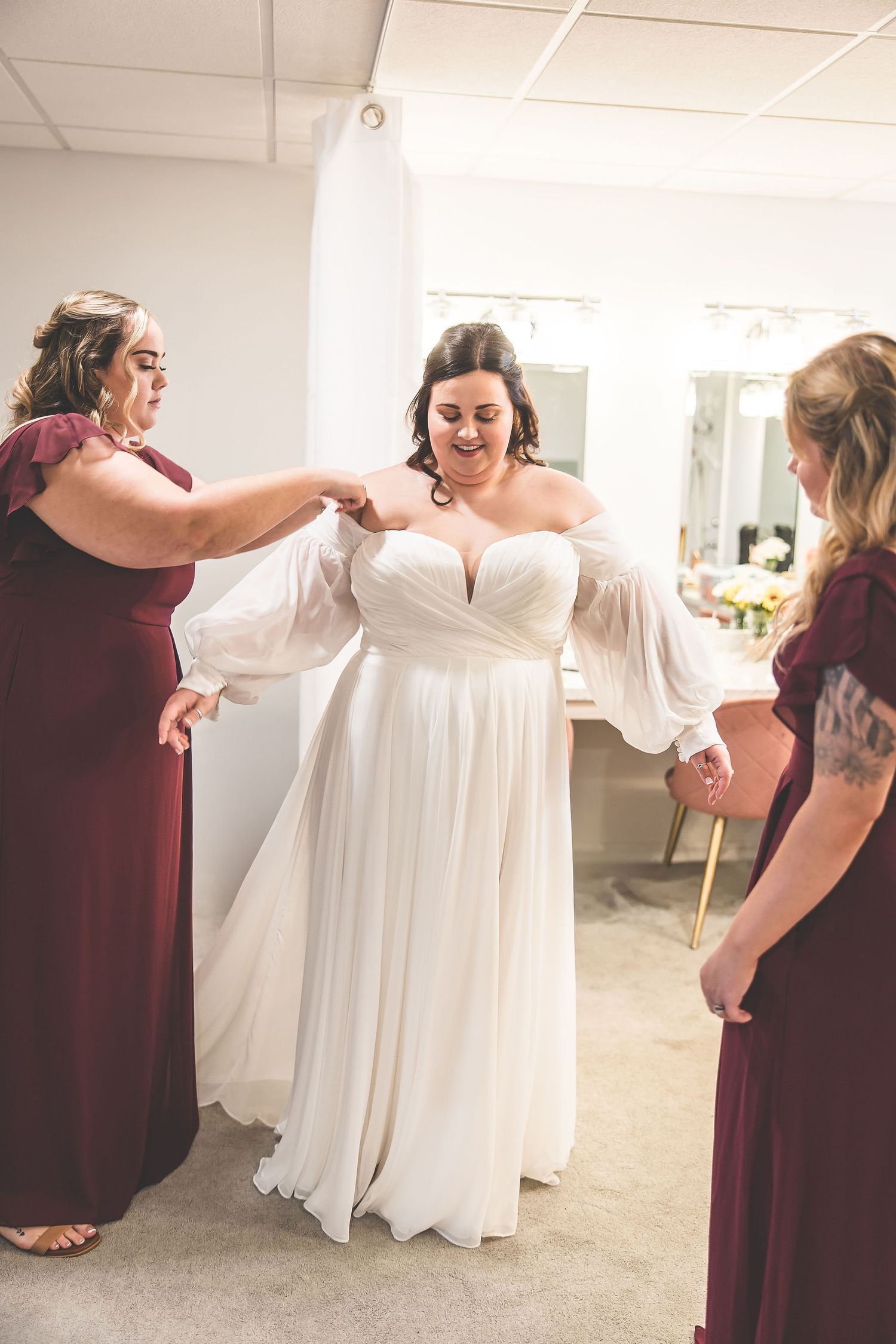 Wedding preparation scene with white gowns and burgundy bridesmaid dresses.