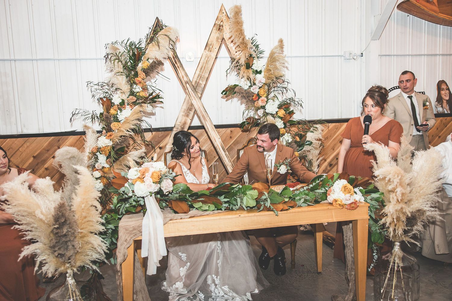 Modern wedding reception space features geometric wooden backdrops and floral installations.