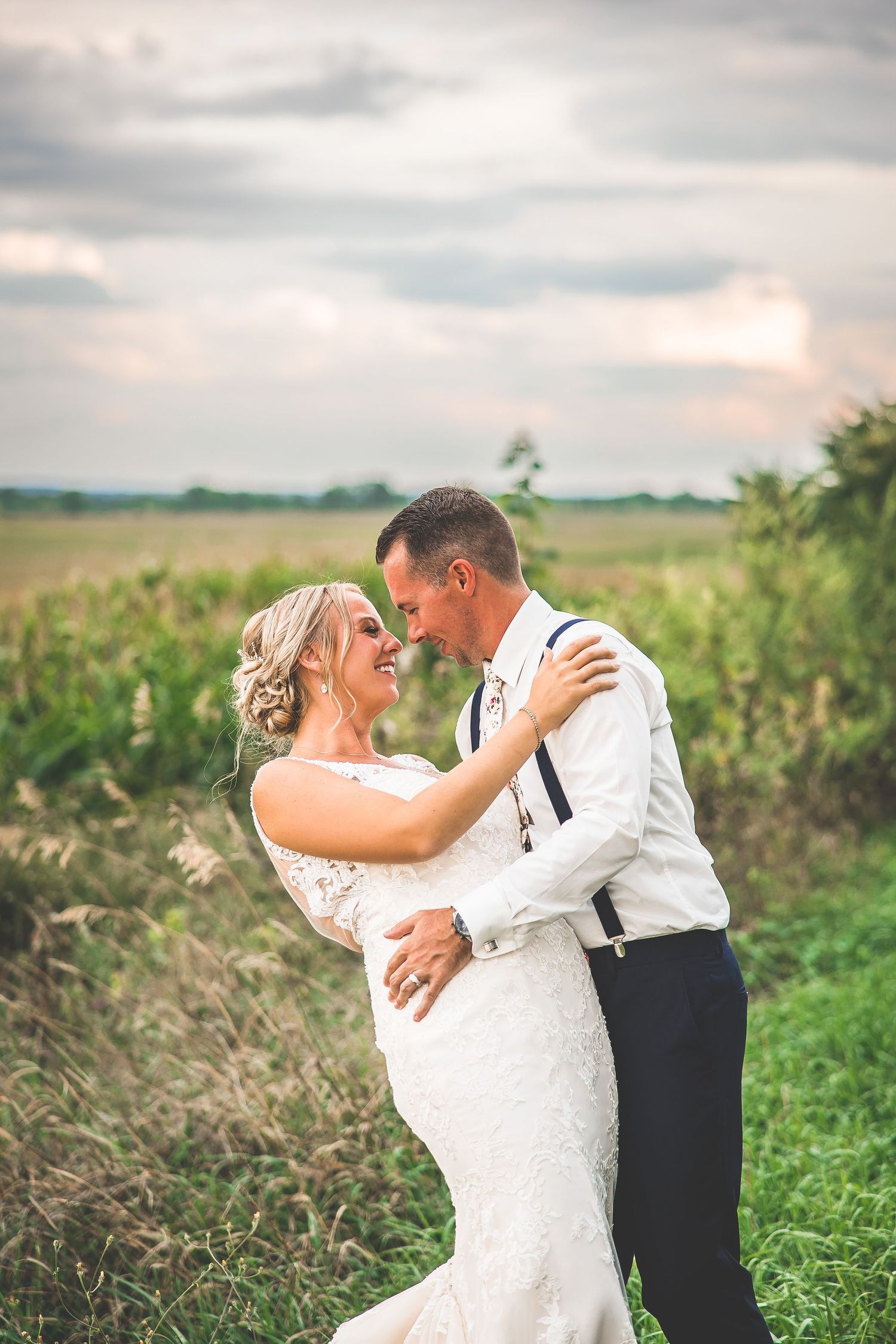 Romantic wedding portraits in a cornfield with dramatic cloudy sky backdrop.