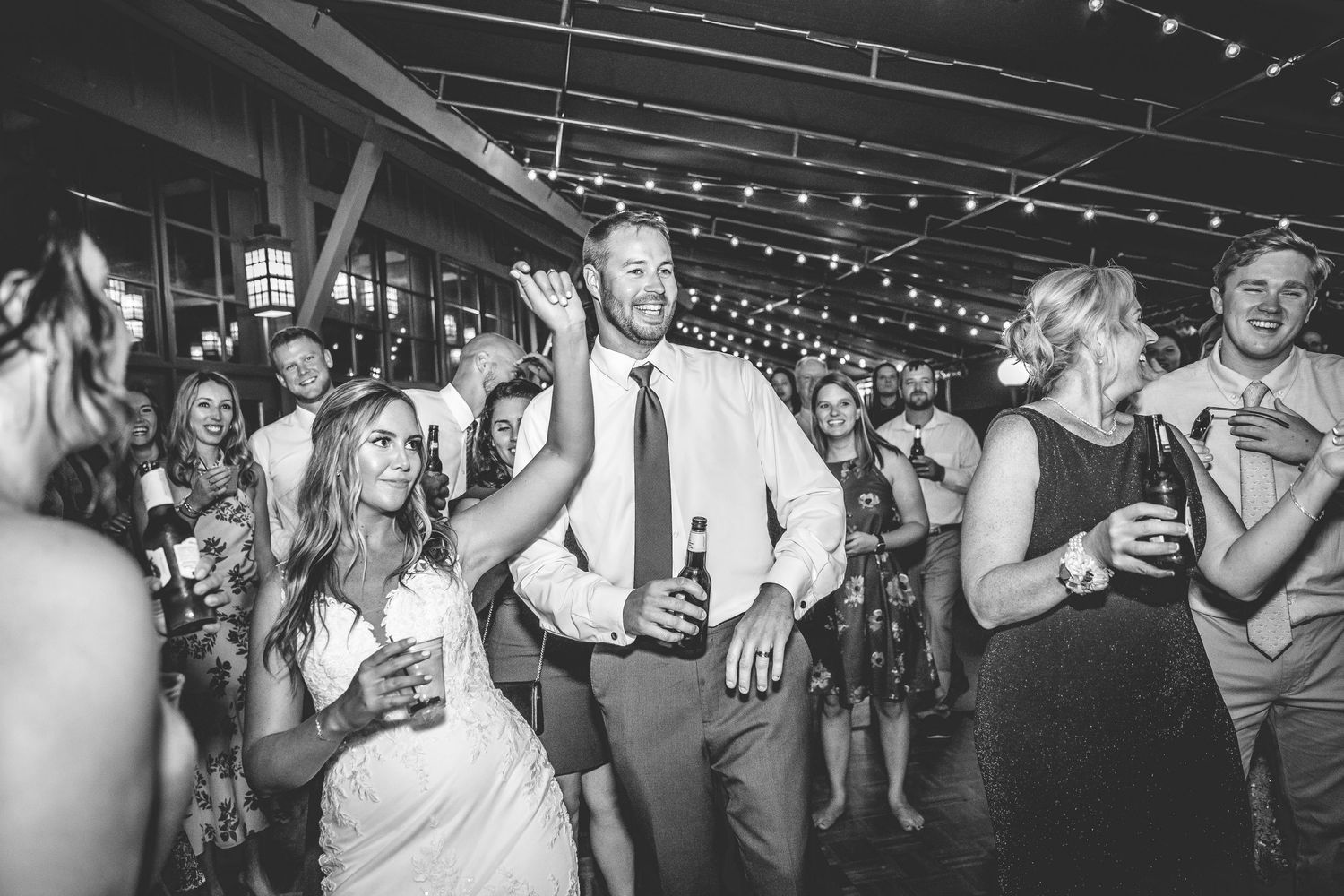 Black and white photo of wedding guests dancing and celebrating at reception.