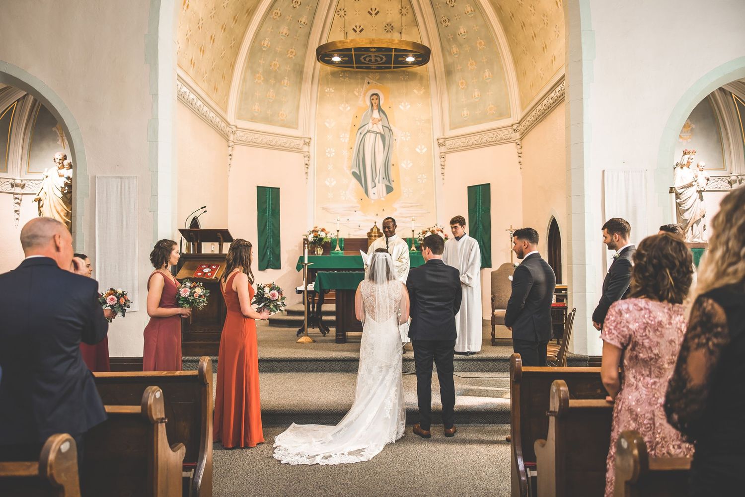 Wedding ceremony in progress inside a bright white church sanctuary with vaulted ceilings.