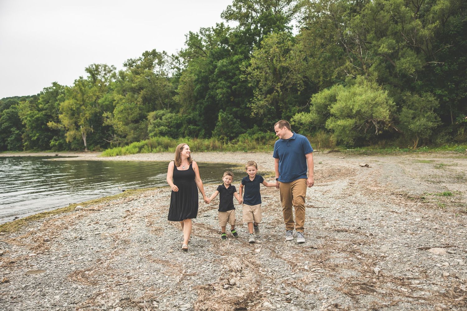 Group walking along a rocky beach shoreline during sunset.