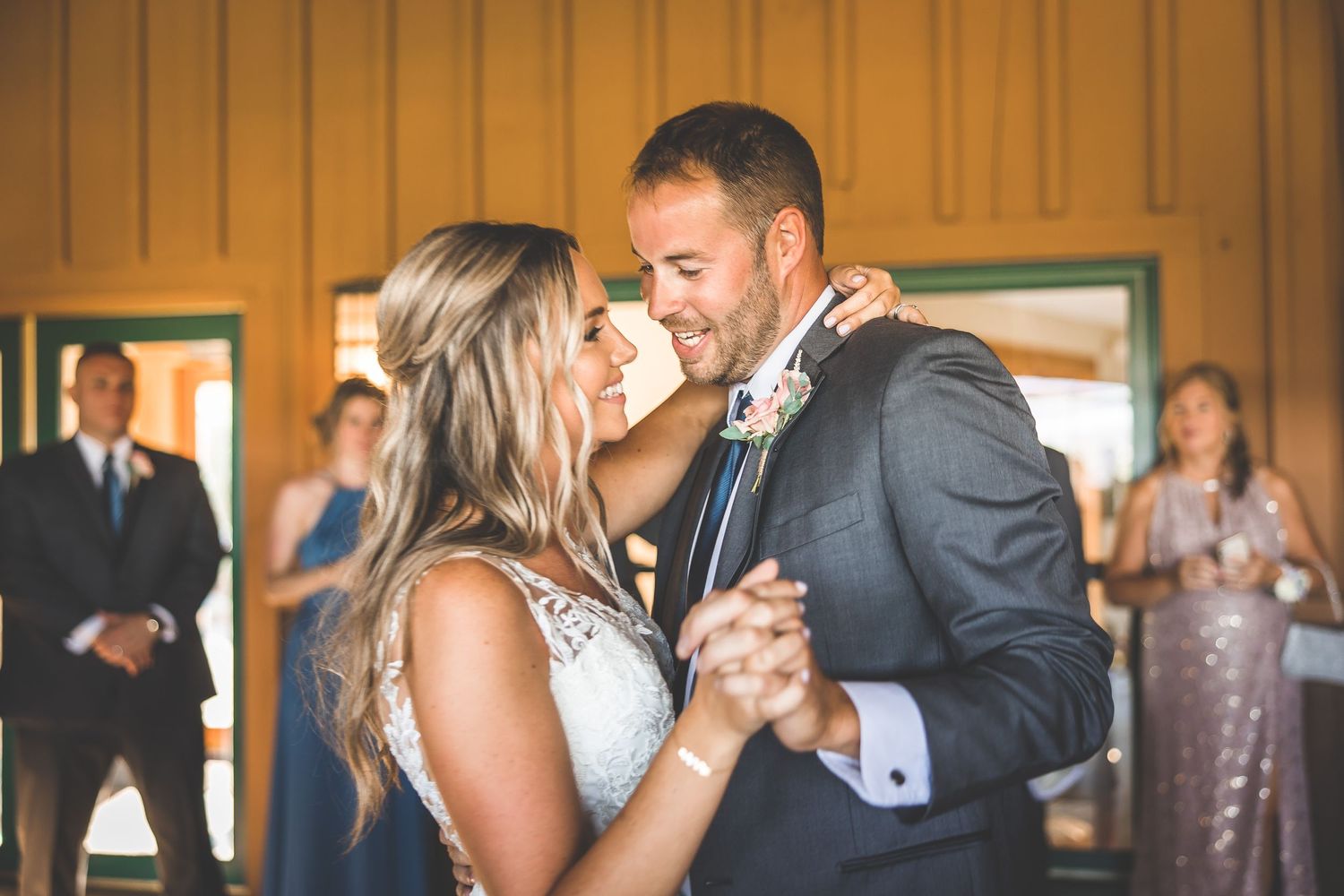 Newlyweds share an intimate dance moment in a rustic venue with wooden walls.