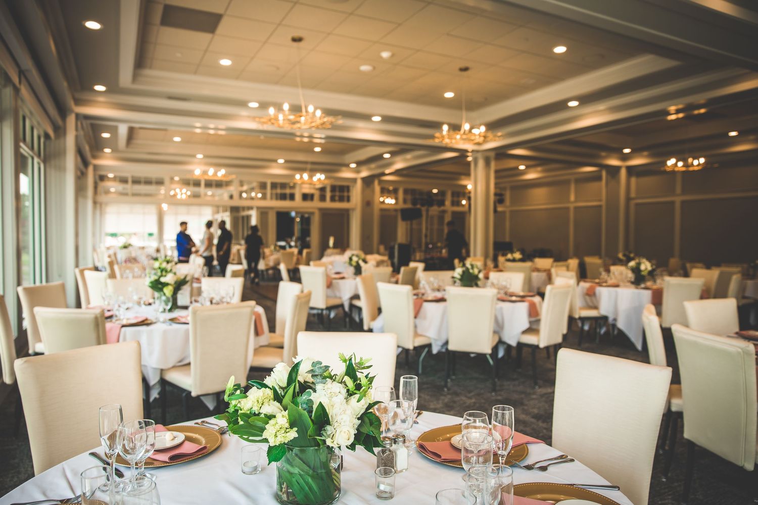 Modern wedding reception venue with elegant table settings and white decor.