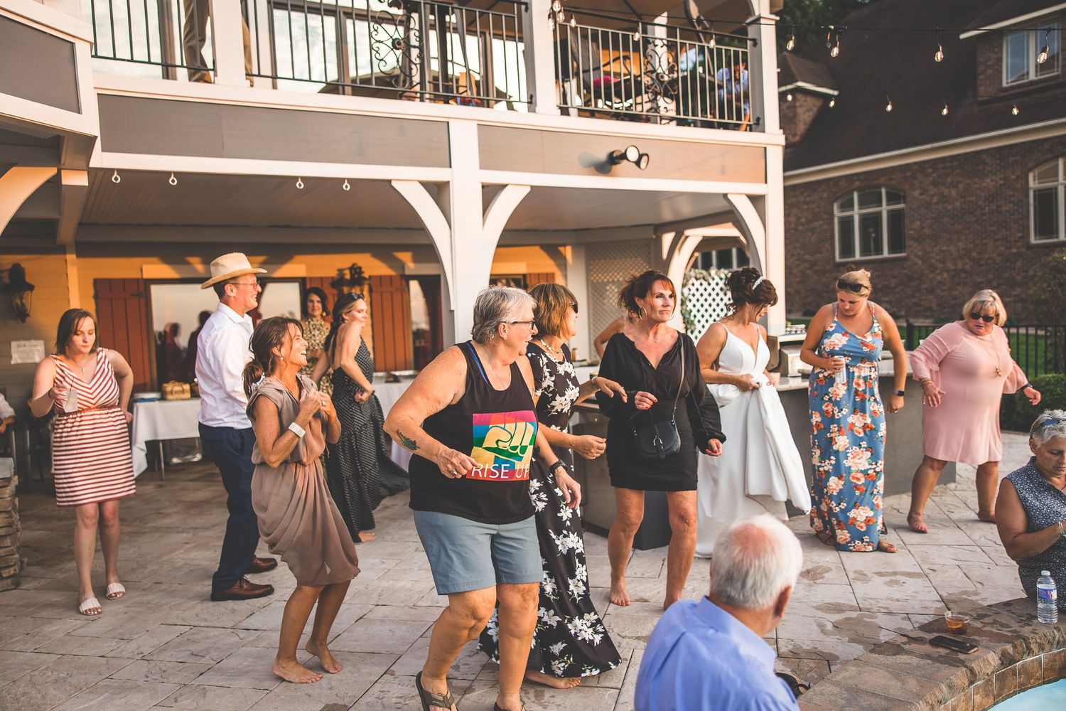 Wedding reception guests dancing and celebrating under a covered outdoor pavilion.