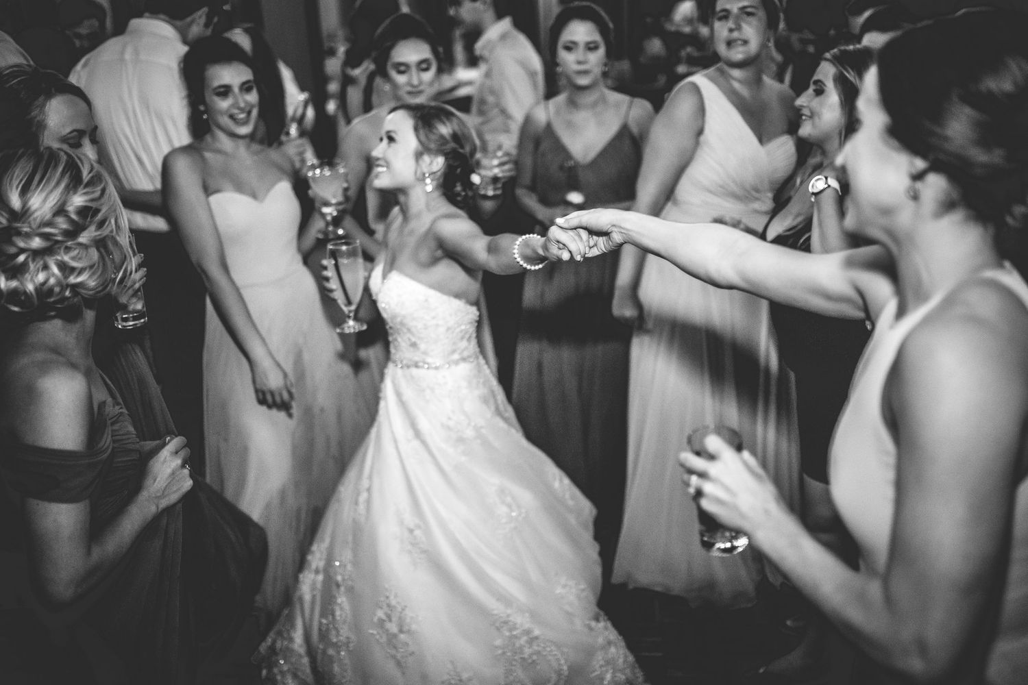 Wedding reception guests dancing and celebrating under dim lighting.